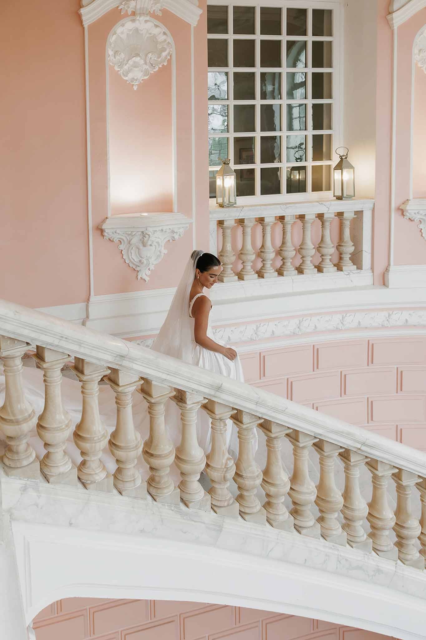 Bride descending marble staircase in ball gown at Domaine Rocabella, Cote d'Azur