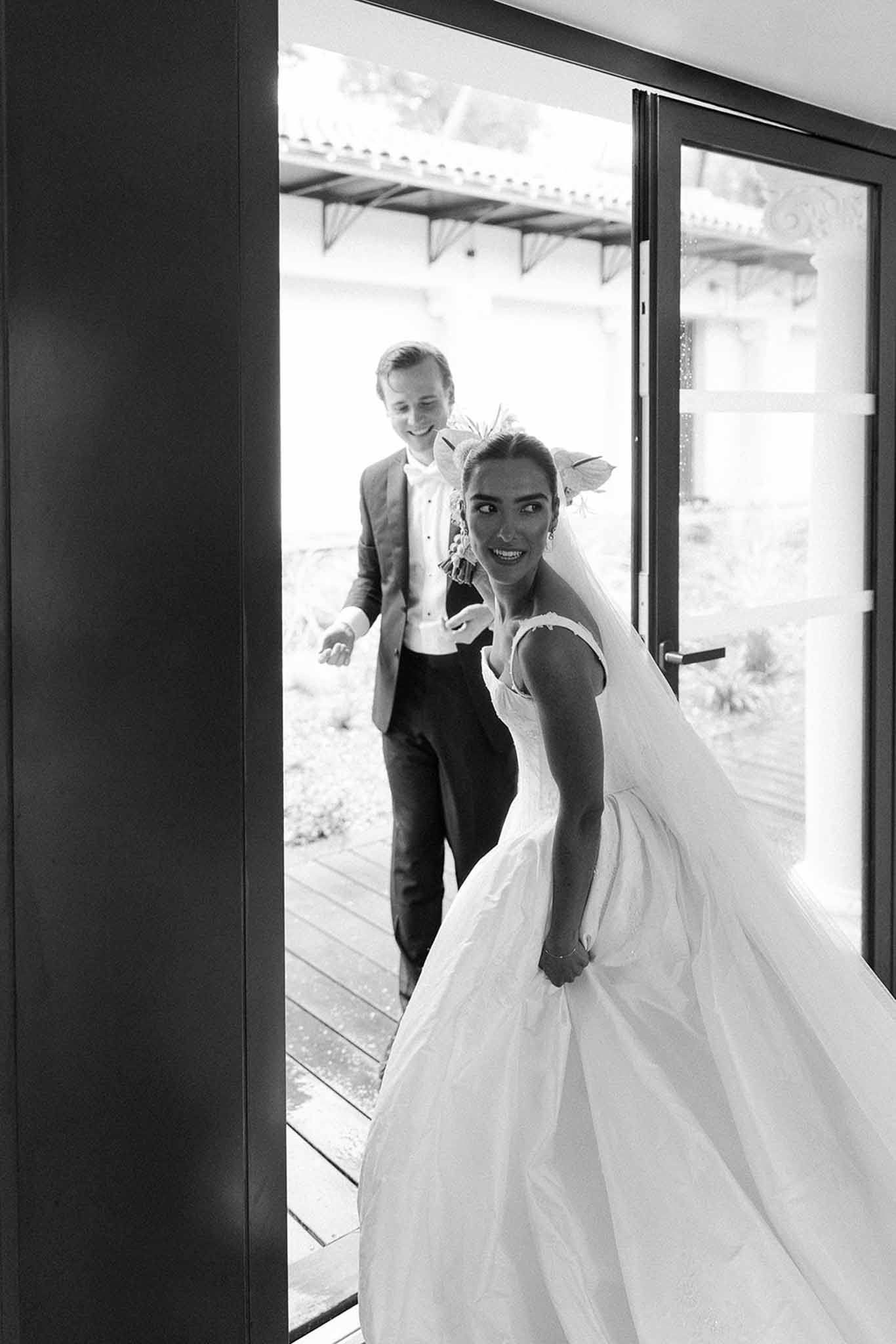 Bride and groom passing through glass doorway at Domaine Rocabella, Cote d'Azur
