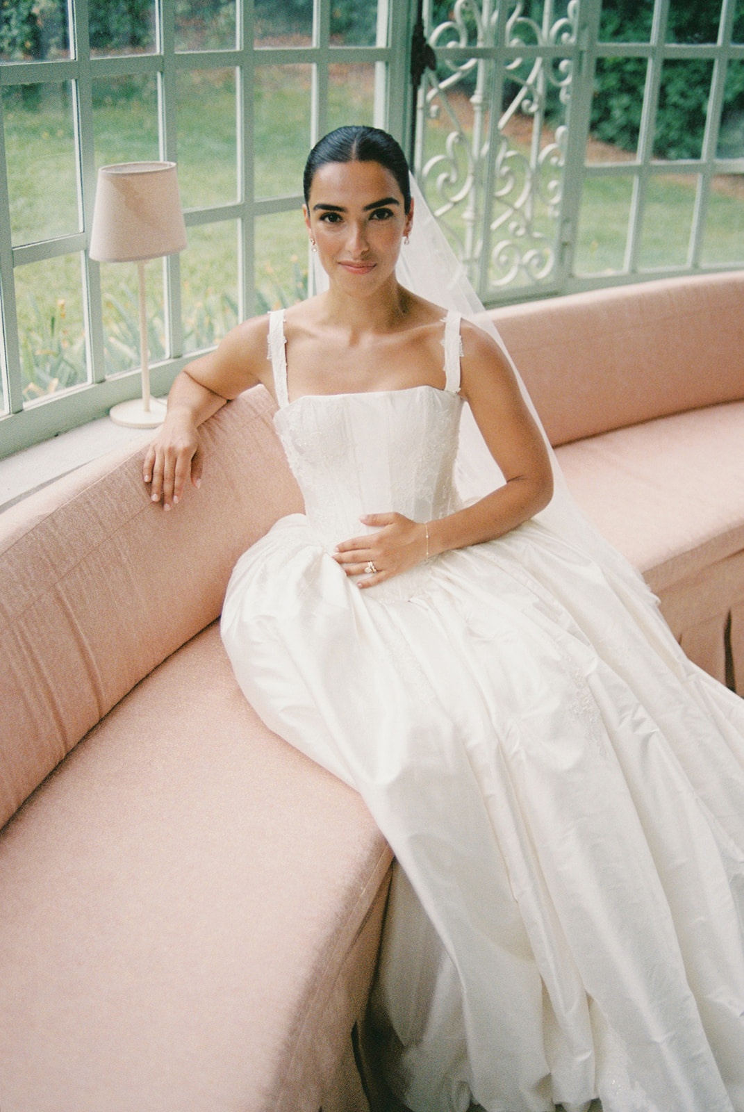 Bride on pink sofa in conservatory at Domaine Rocabella