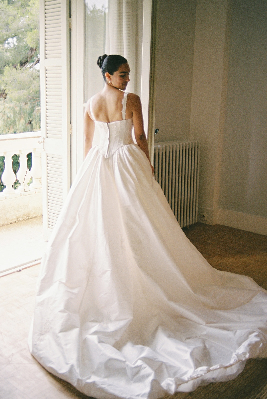 Bride looking out to Mediterranean from bedroom at Domaine Rocabella