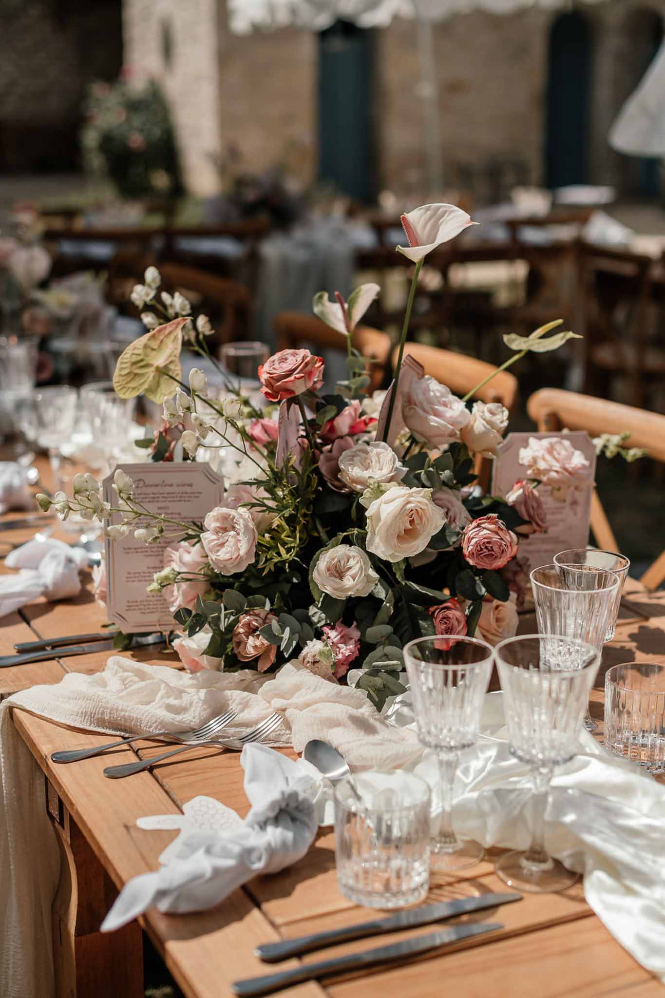 Centrepiece of blush roses, white calla lilies, and anthurium with gauze runner and black cutlery