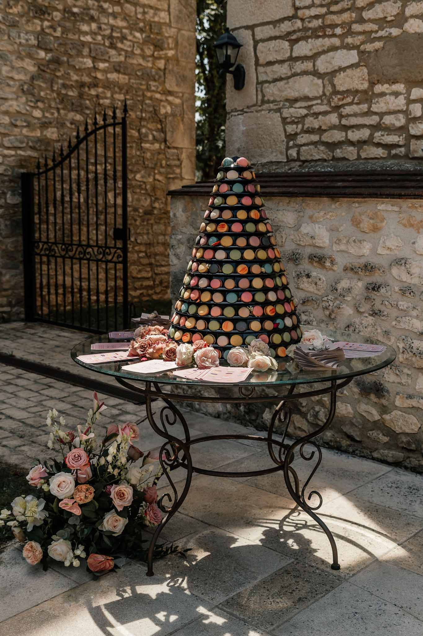 Multicolored macaron tower on wrought iron table with garden roses at chateau courtyard