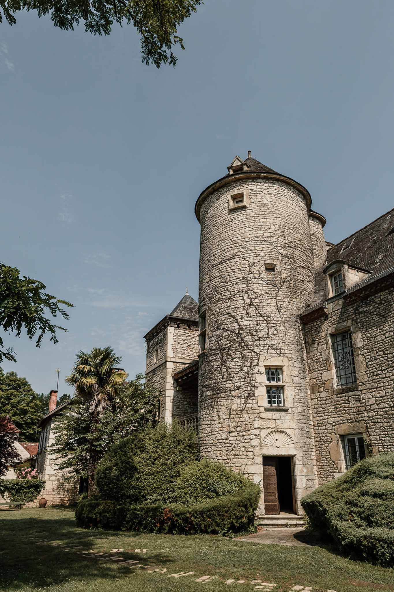 French chateau stone tower with conical slate roof and carved doorway in golden hour light