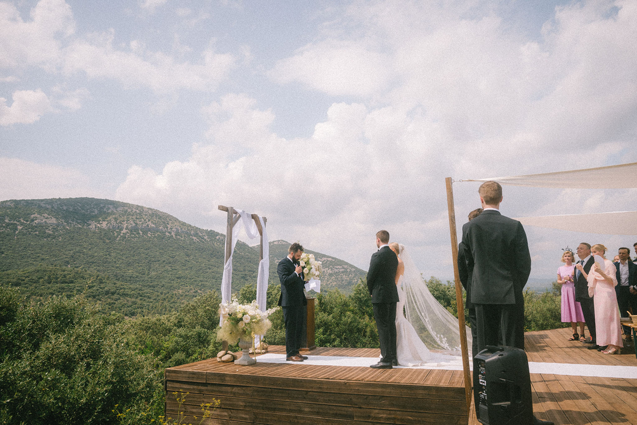 Outdoor wedding ceremony on wooden deck with floral arch and panoramic mountain backdrop in southern France