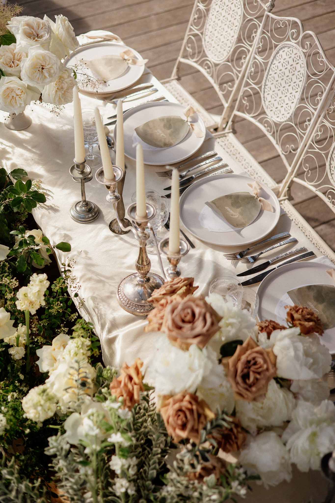 Table with sage napkins, silver candelabra, and ivory and caramel rose runner on cream satin runner