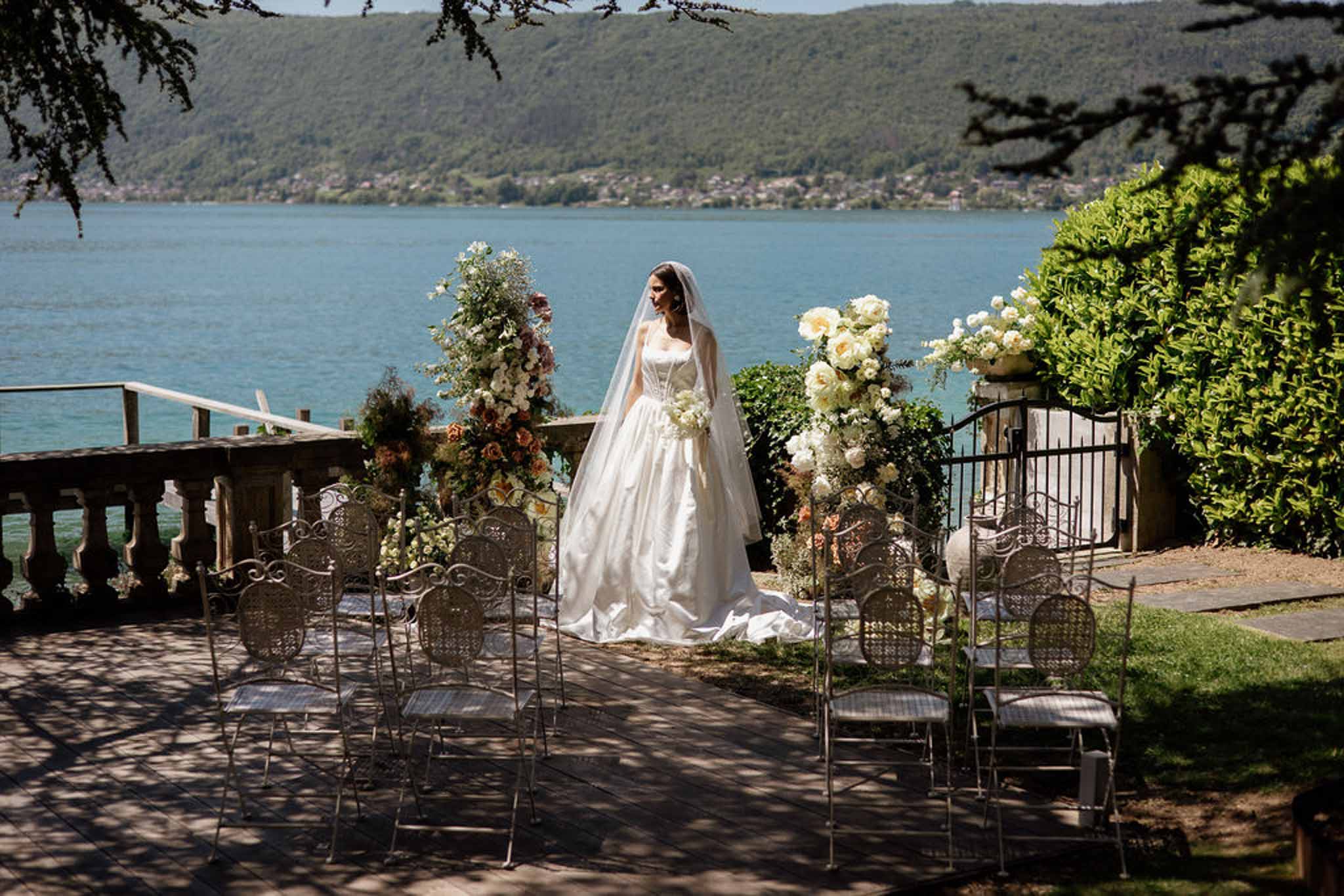 Bride with cathedral veil at lakeside ceremony terrace with white and terracotta altar arrangements