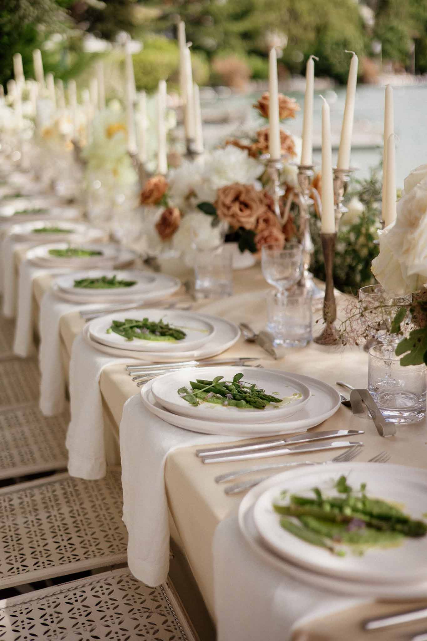 Outdoor reception table with ivory peonies terracotta roses silver candelabras and plated starter