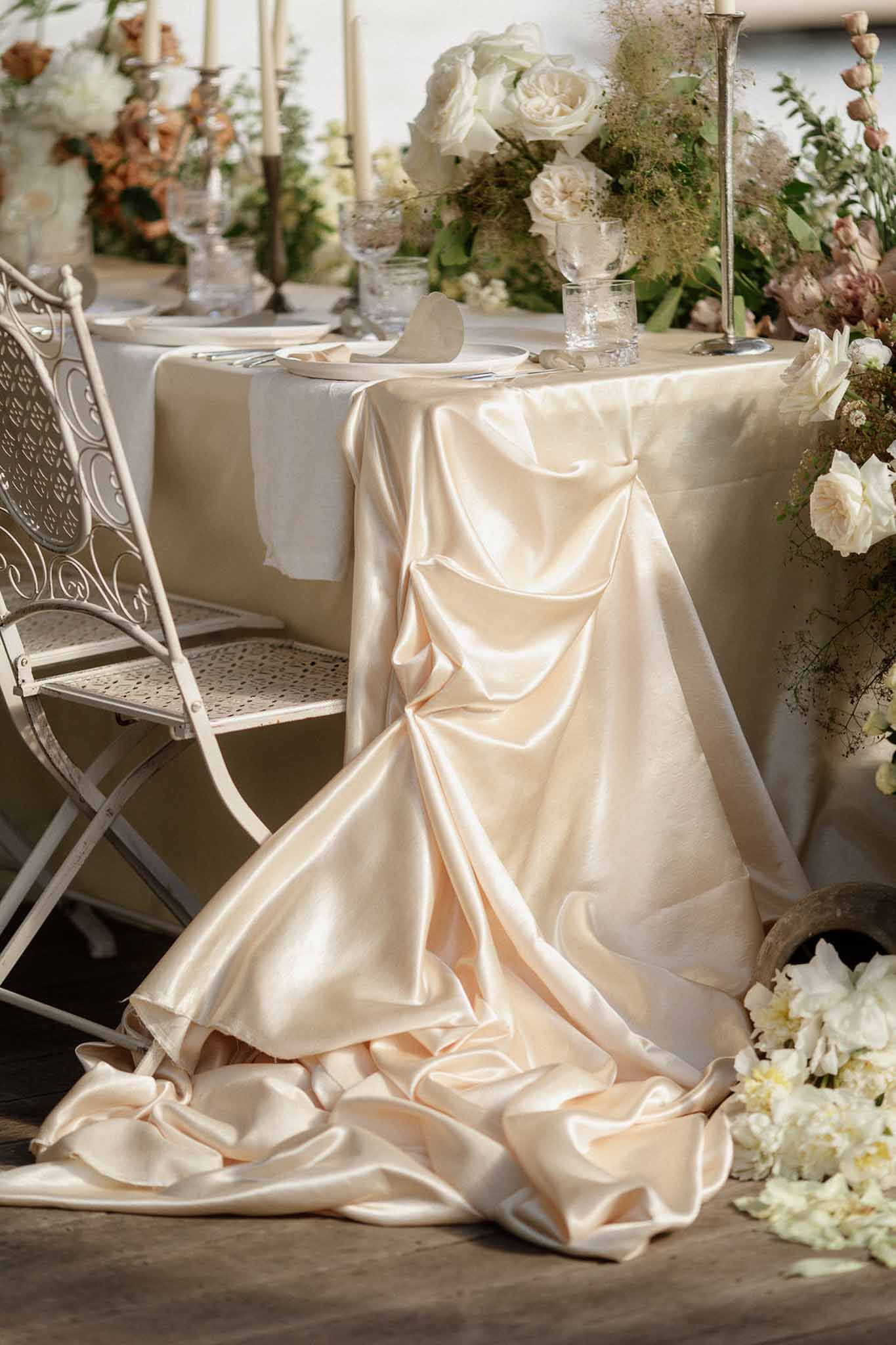 Champagne satin draped sweetheart table with ivory peonies, garden roses, and dusty mauve blooms with silver candles