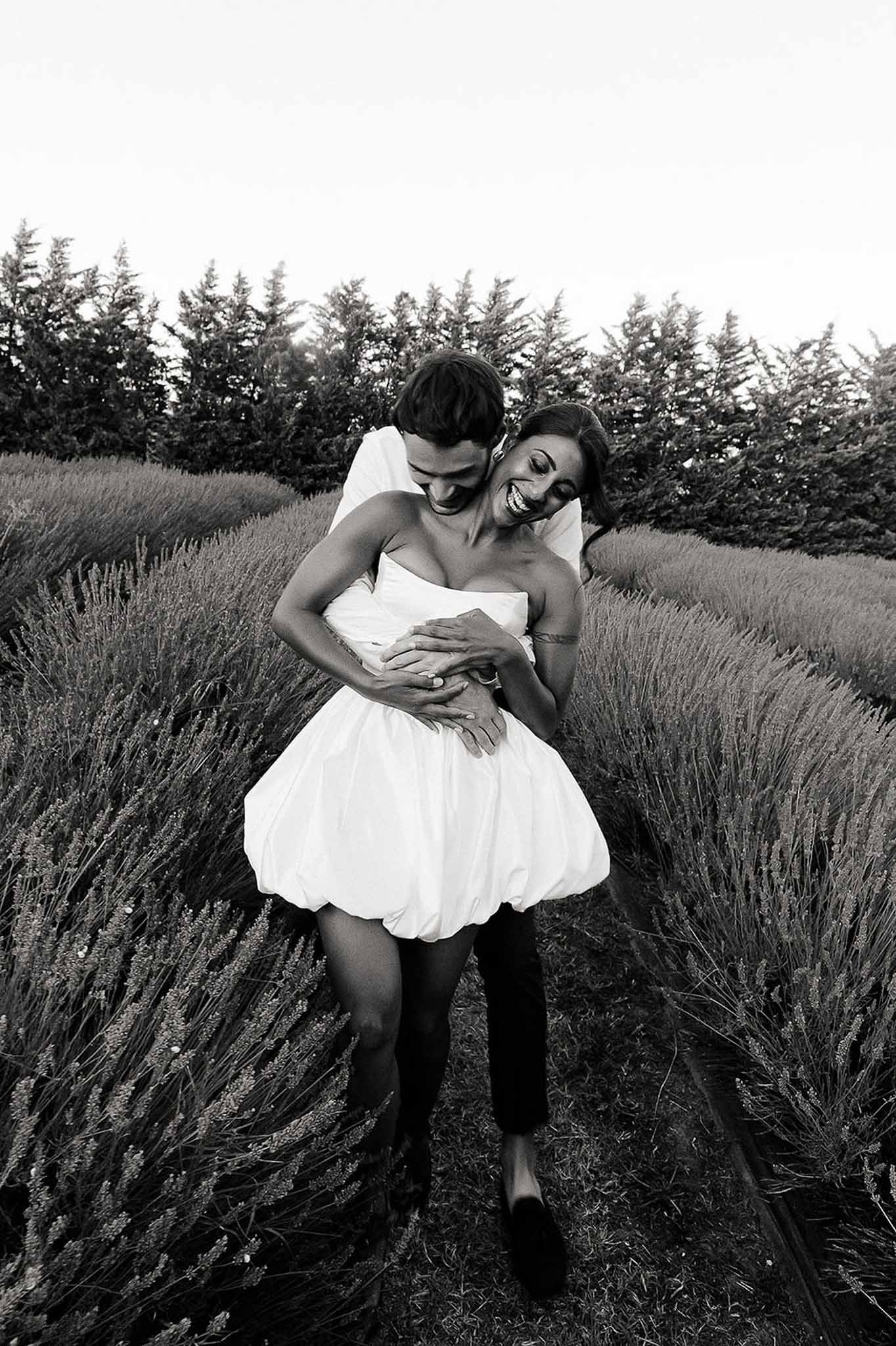 Bride in short dress and groom hugging in lavender field, Bastide des Barattes Provence