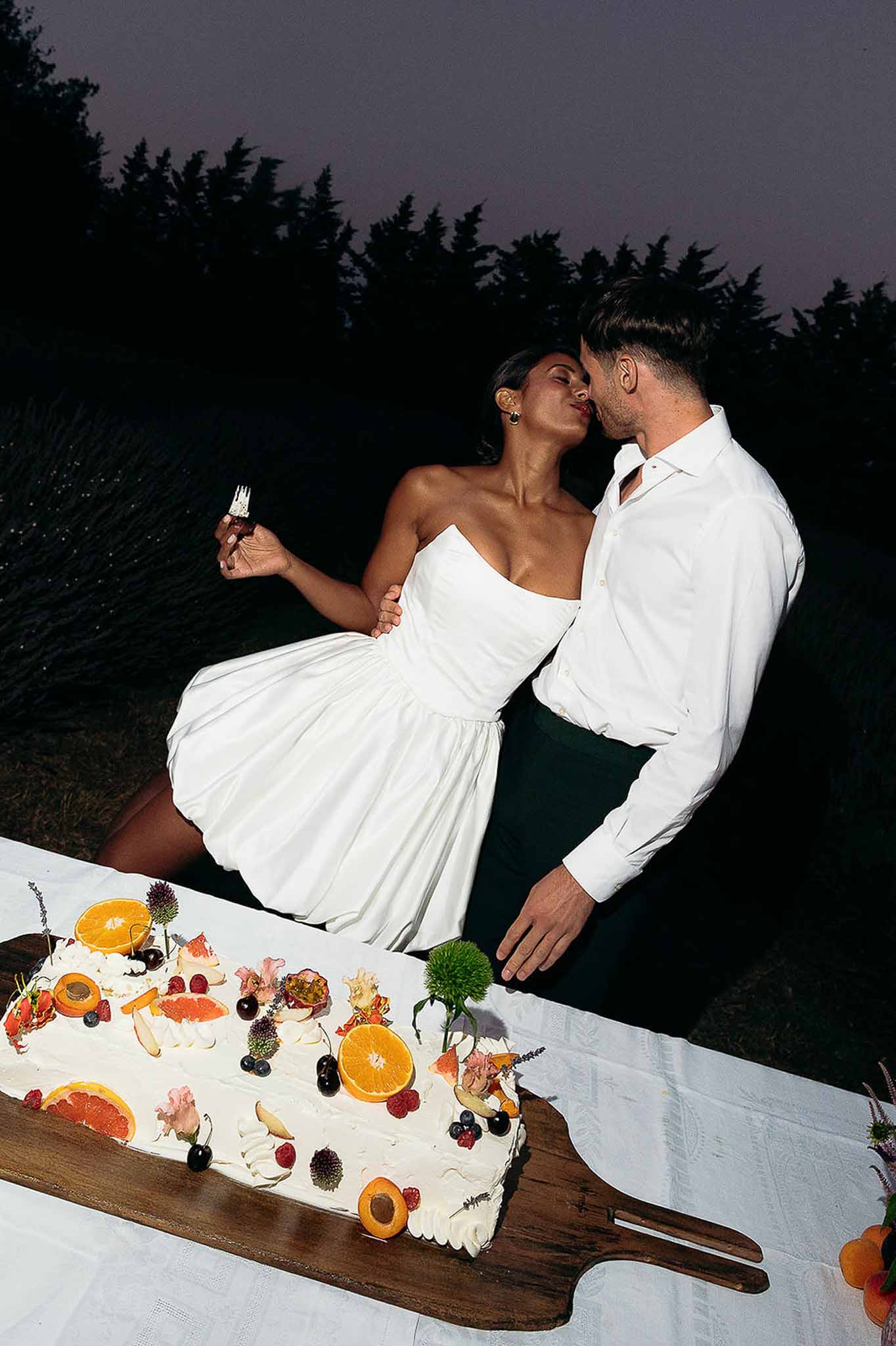 Couple cutting the wedding cake and sharing a kiss at the Bastide des Barattes reception