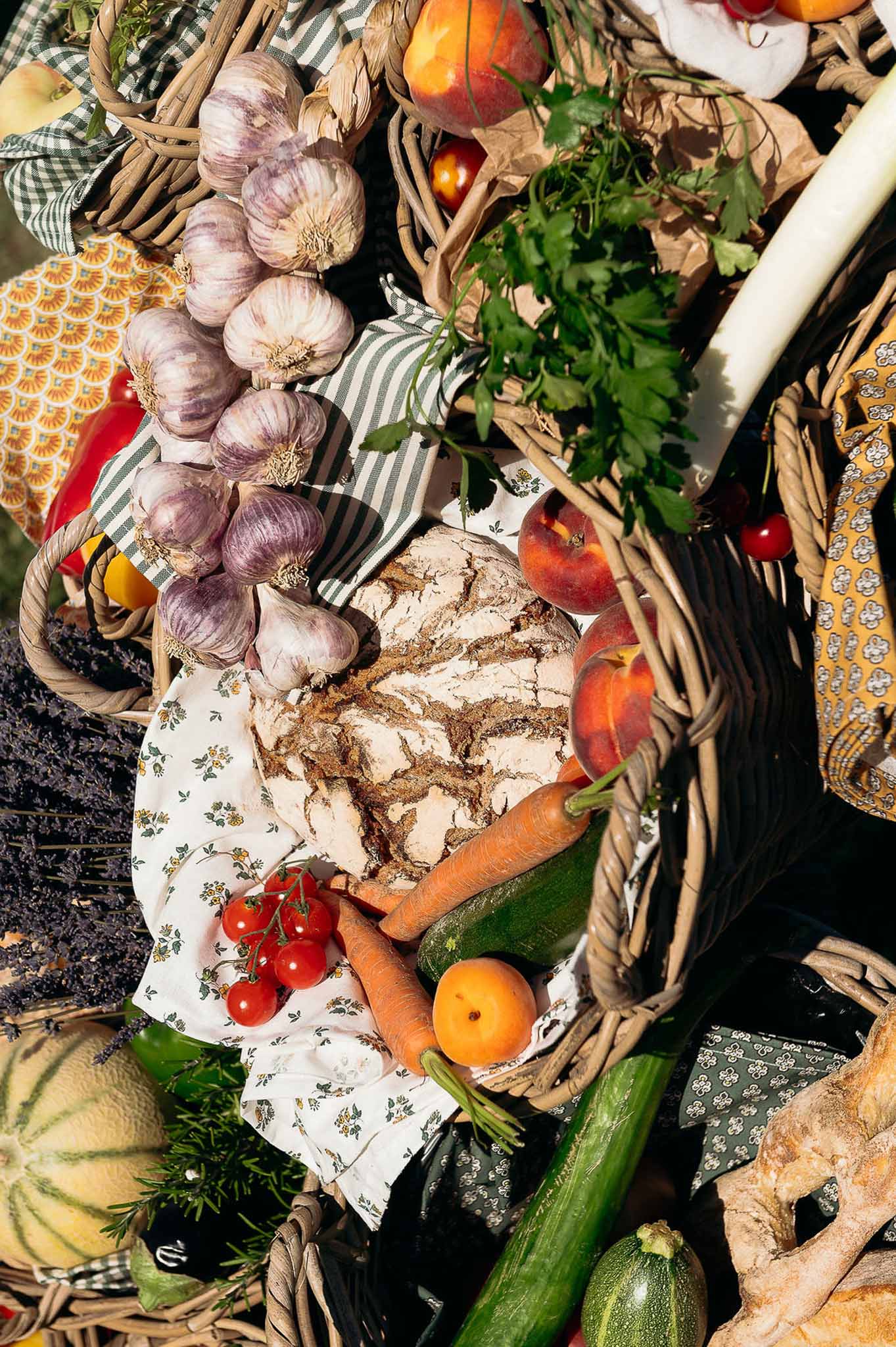 Sunlit close-up of bread, vegetables and floral basket centerpiece at Bastide des Barattes reception