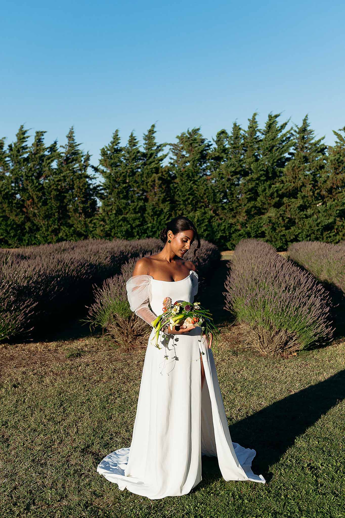 Bride in off-shoulder gown with high slit standing in lavender field at golden hour, Bastide des Barattes