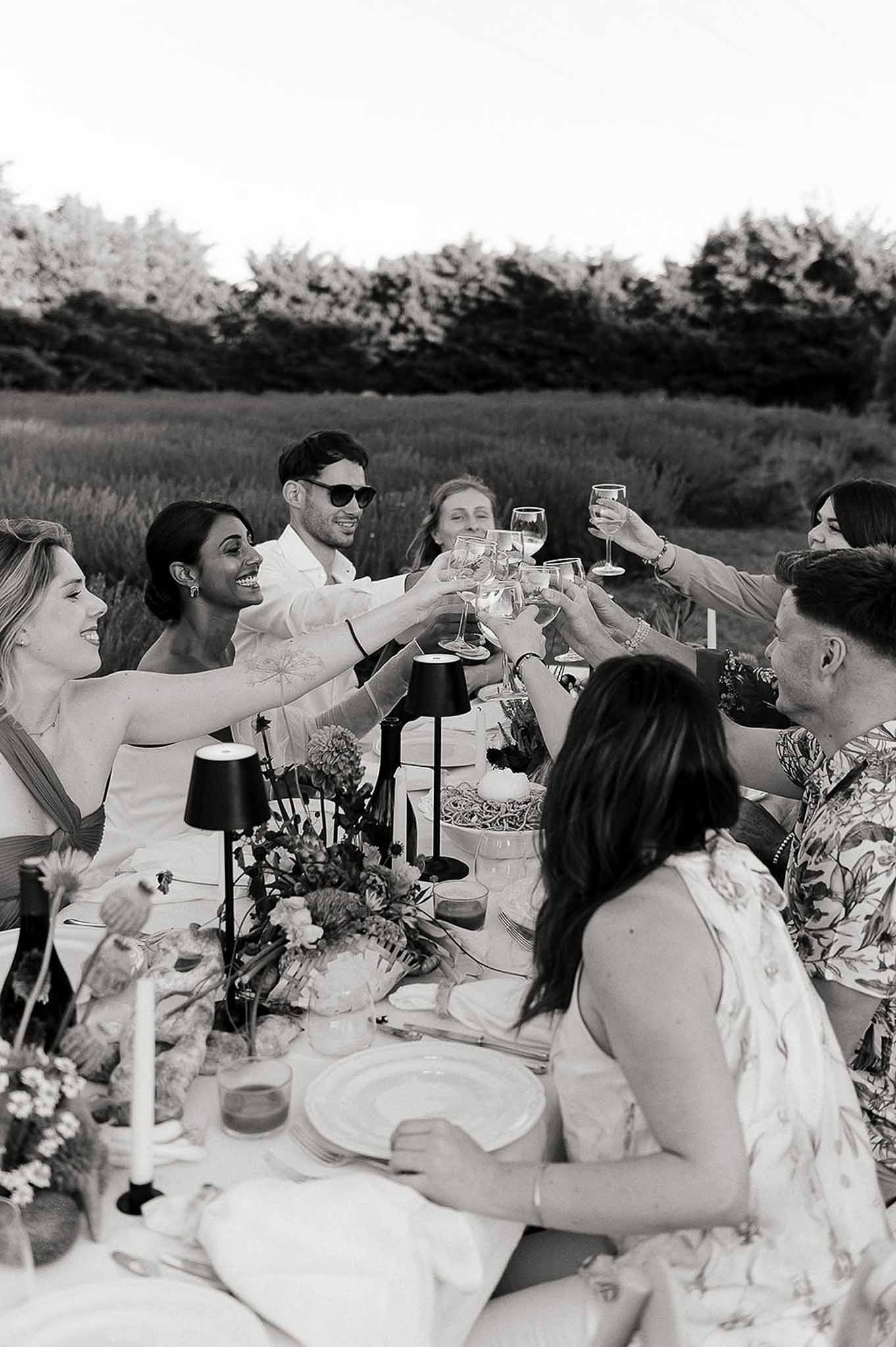 Guests seated at the market-inspired reception table raising glasses for a toast, Bastide des Barattes