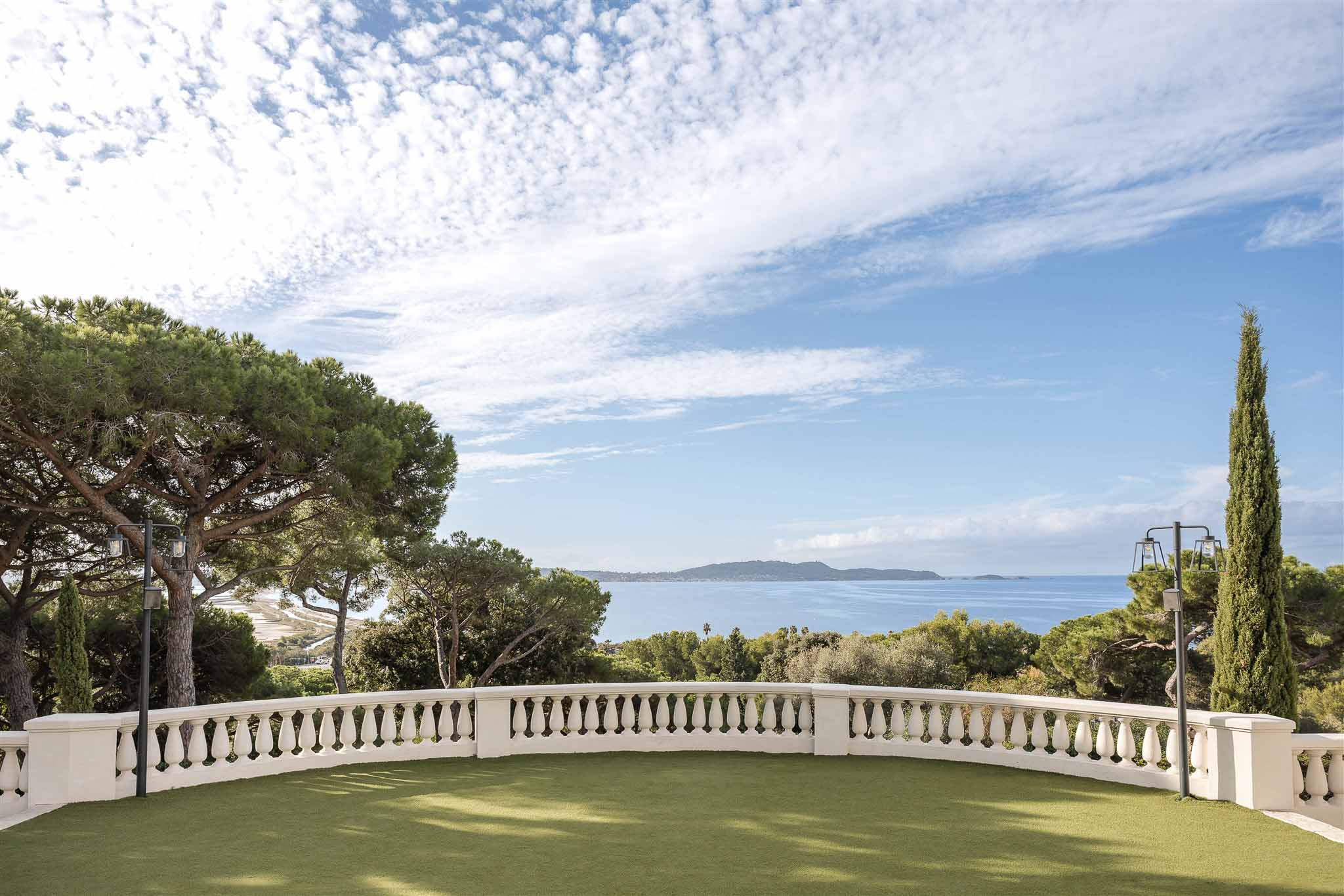 Curved white stone balustrade terrace with lamp posts overlooking panoramic sea view on French Riviera