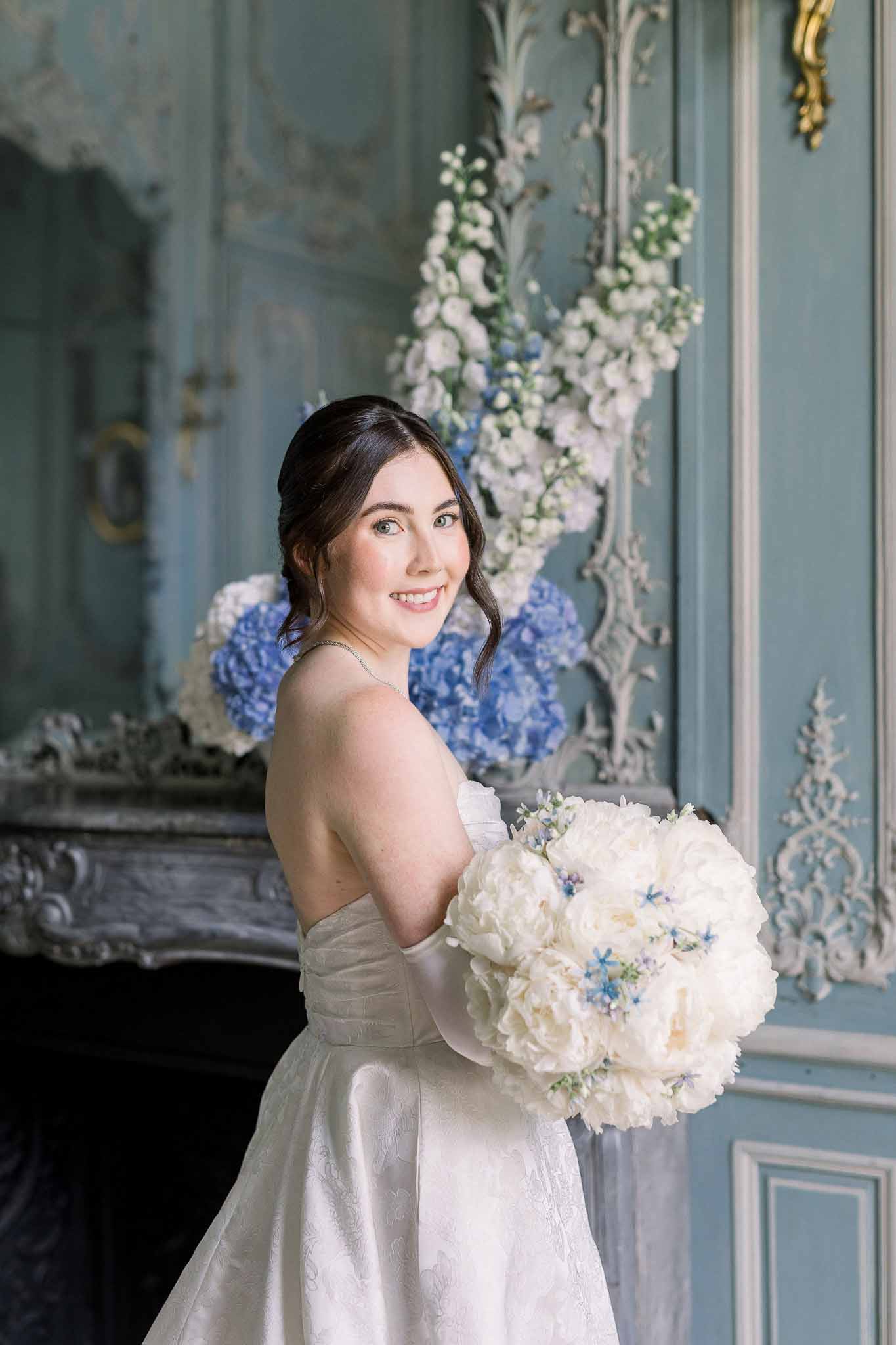 Bride holding white peony and blue forget-me-not bouquet in powder blue panelled chateau salon