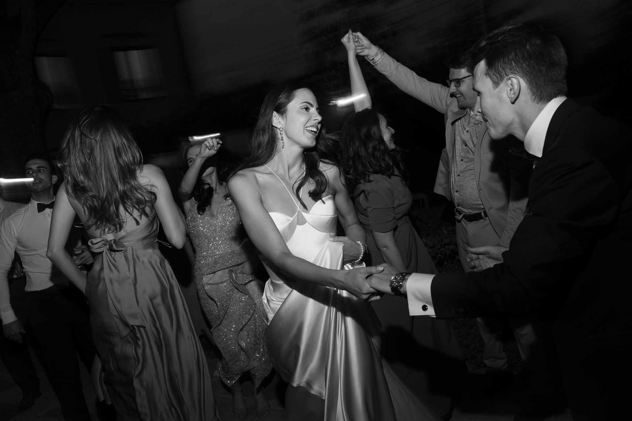 Bride and groom dancing with guests on the dance floor during wedding reception in black and white