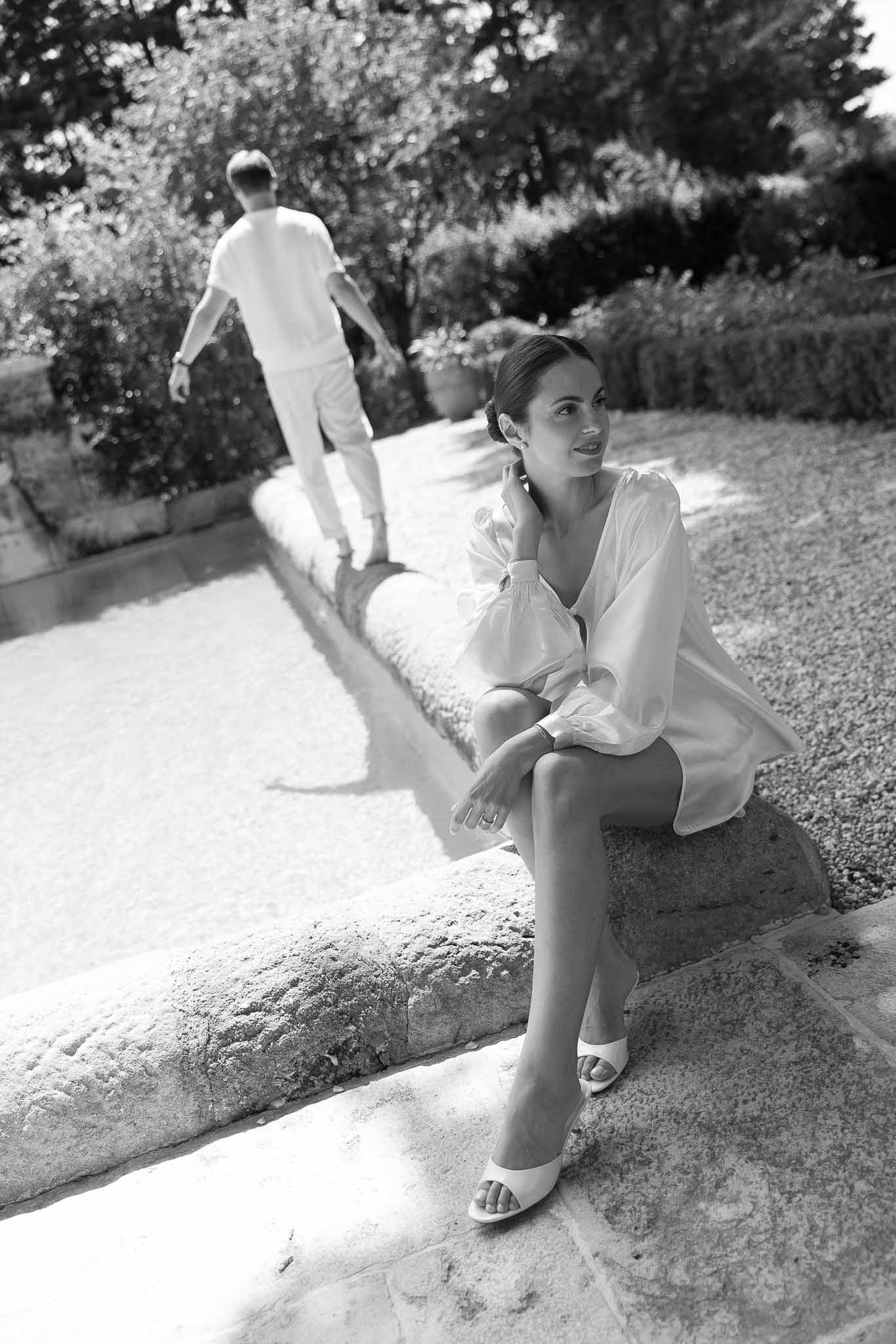 Black and white photo of bride and groom walking hand in hand in a garden