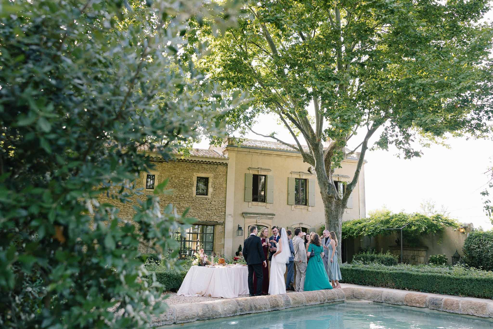Guests mingling with bride and groom by the pool at a Provencal stone manor during cocktail hour