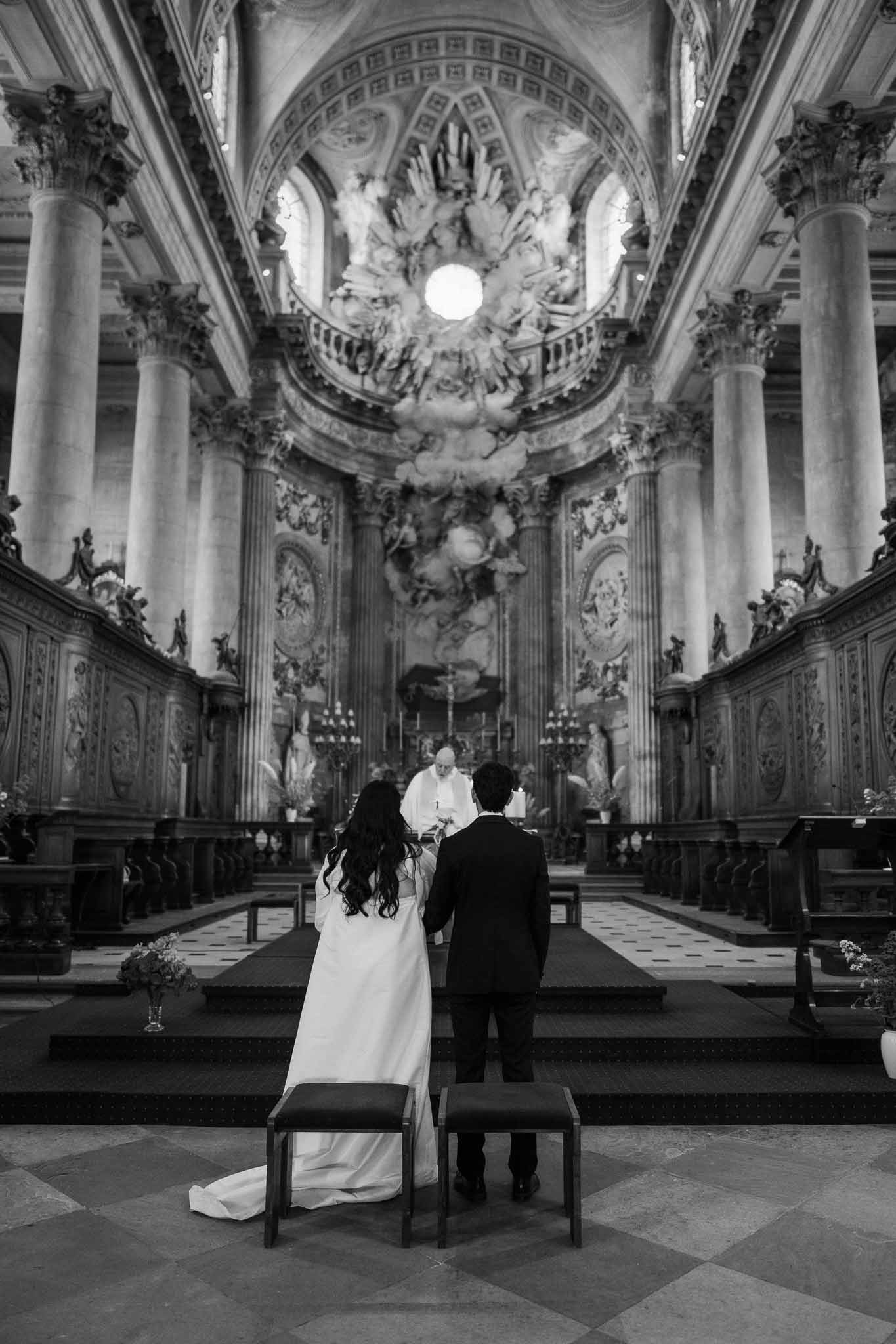 Black and white ceremony in baroque church with Corinthian columns and sculpted domed ceiling