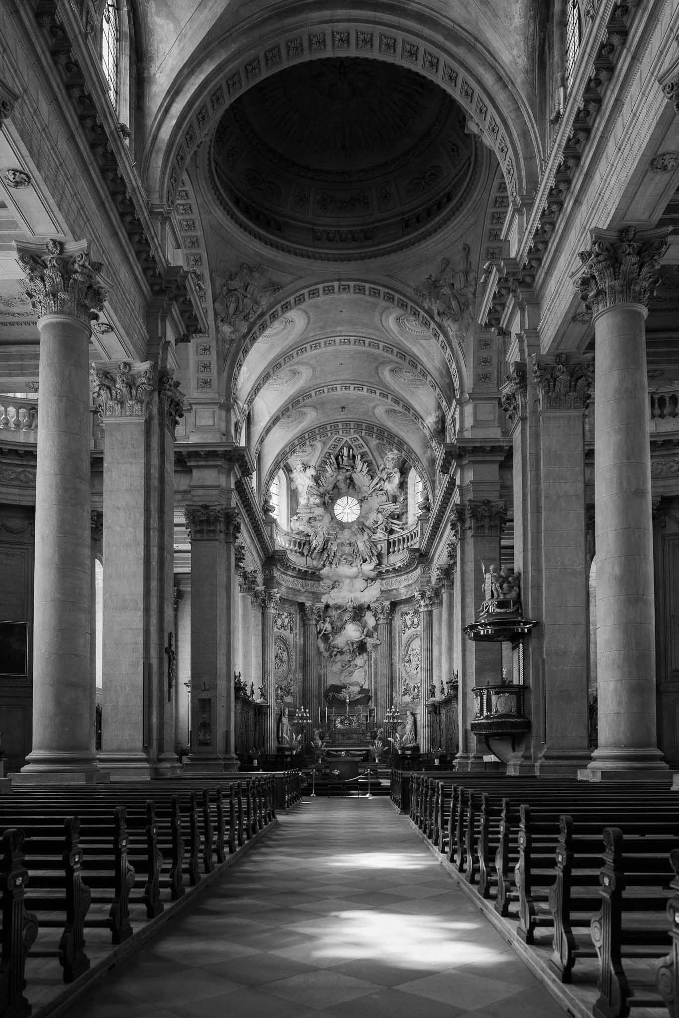 Black and white interior of Baroque church nave with Corinthian columns and sculpted altarpiece