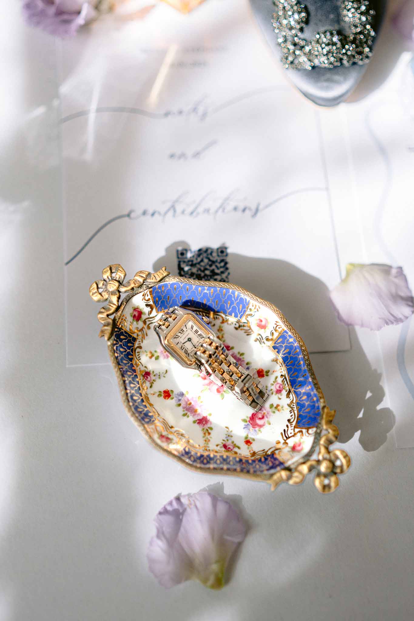 Cartier-style watch on cobalt blue porcelain dish with lavender petals crystal bridal shoe and calligraphy card
