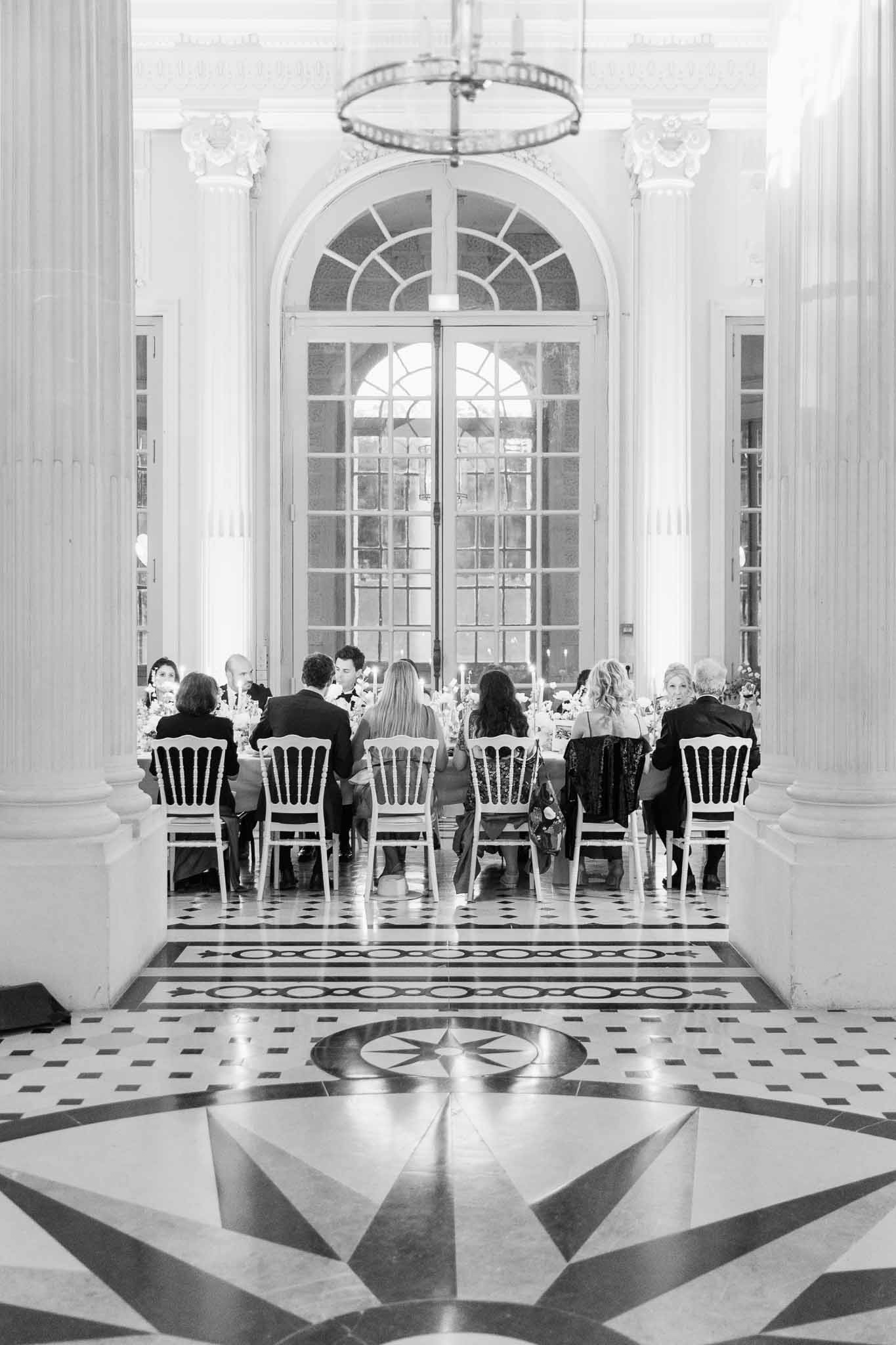 Black and white dinner in neoclassical hall with compass rose marble floor and arched French doors