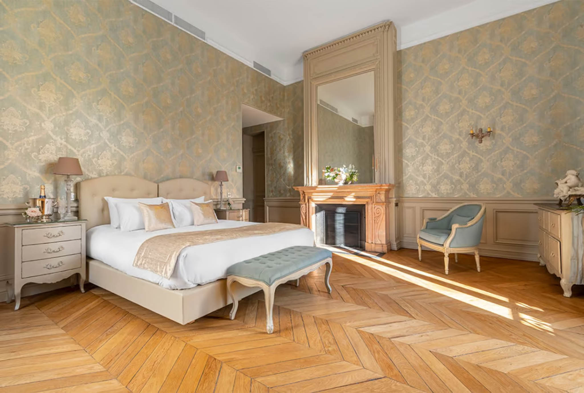 Bridal suite with sage damask panels, cream bed with gold pillows, powder blue bench, and champagne bucket