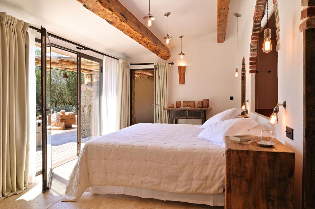 Rustic-modern guest room with exposed beams, brick arch, Edison pendants, and glass doors to wooden terrace