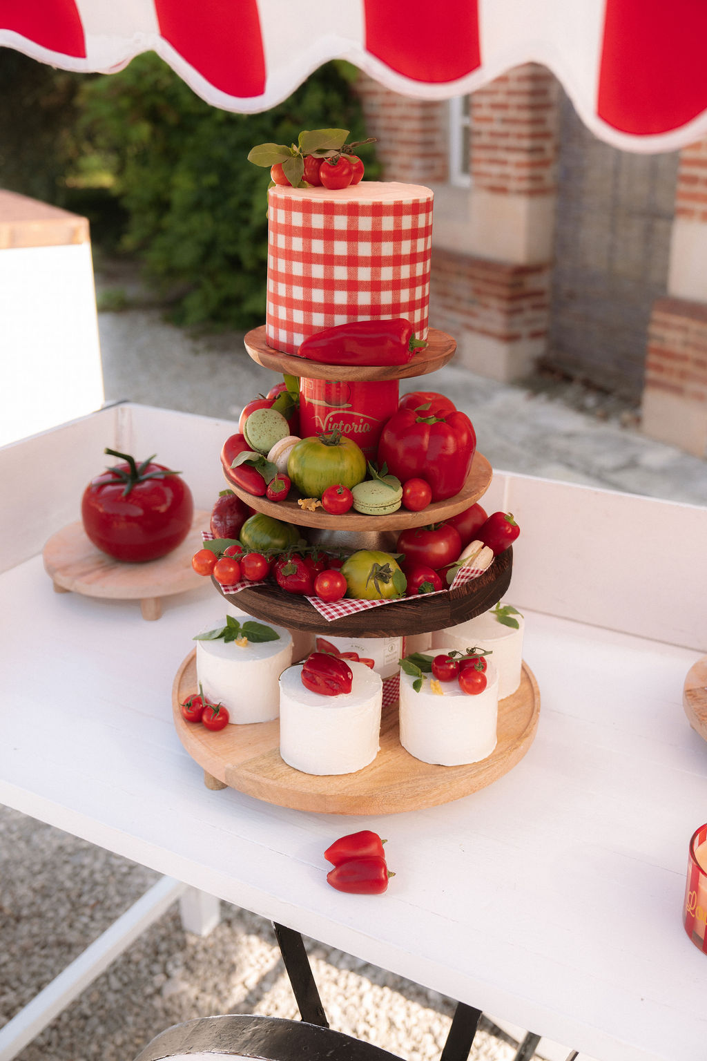 Tiered wooden stand with tomato-themed cake red and green macarons and heirloom tomato display