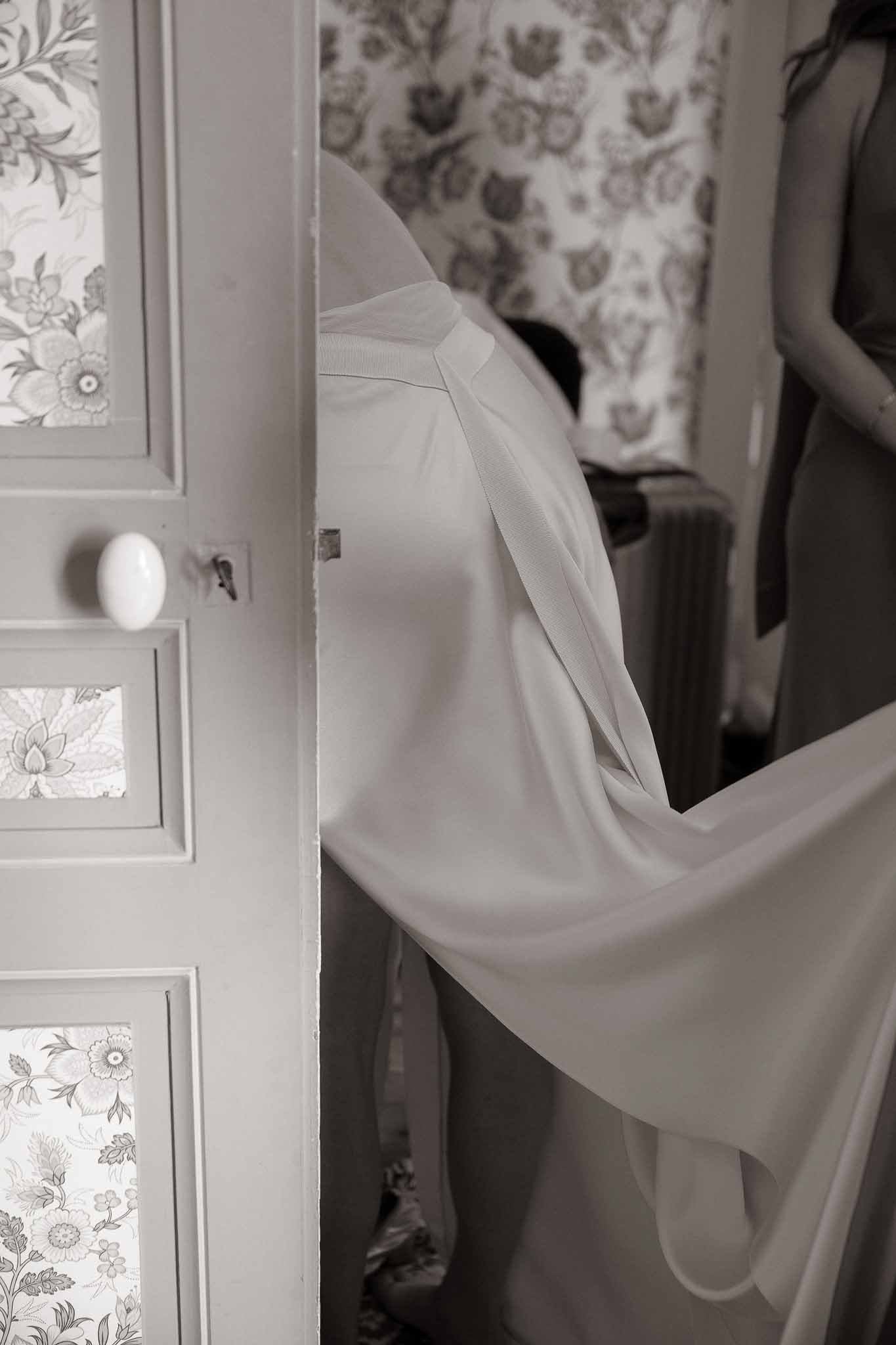 Black and white close-up of wedding dress bodice in doorway with painted floral door panel