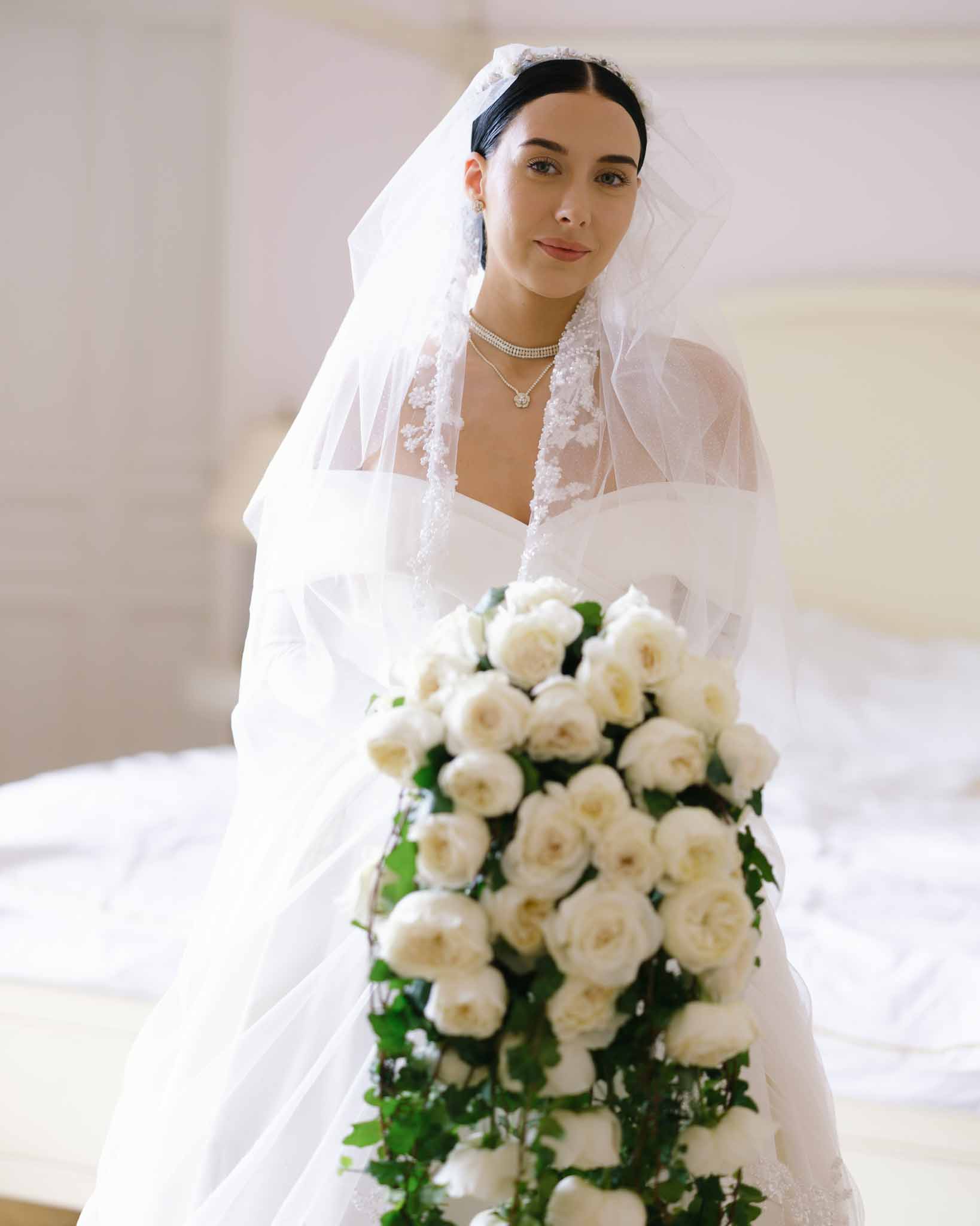 Bride in off-shoulder gown with cathedral lace veil and cascading white garden rose bouquet with trailing ivy