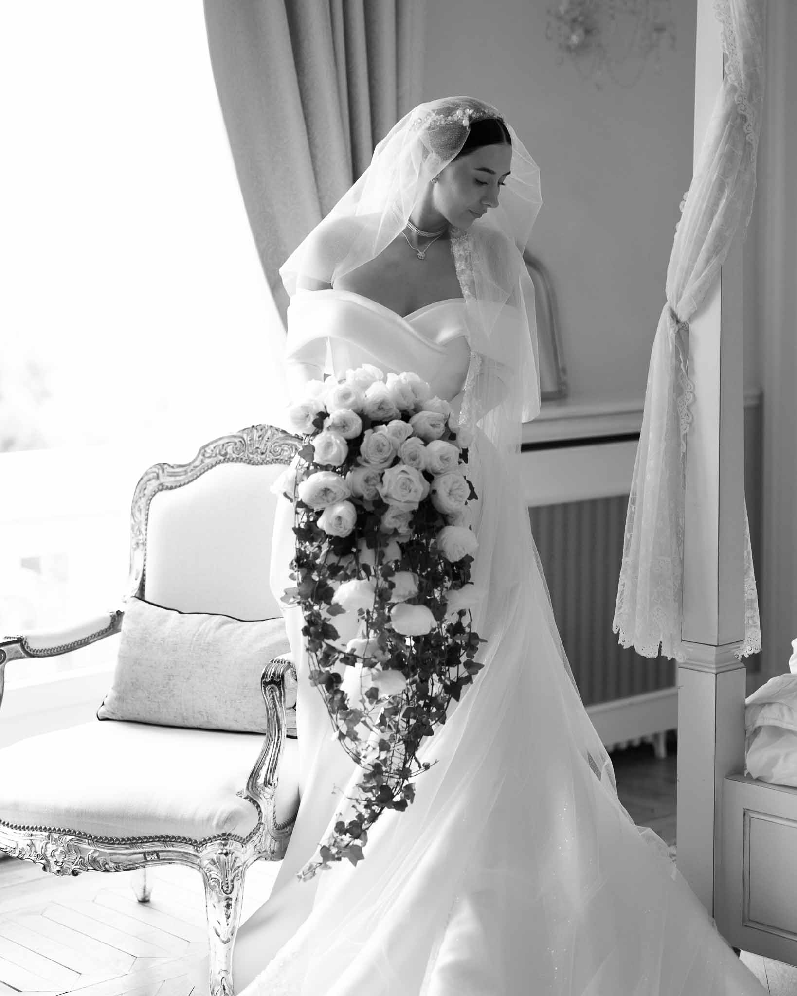 Black and white bride in mermaid gown with cathedral veil holding cascading rose and ivy bouquet in gilded room