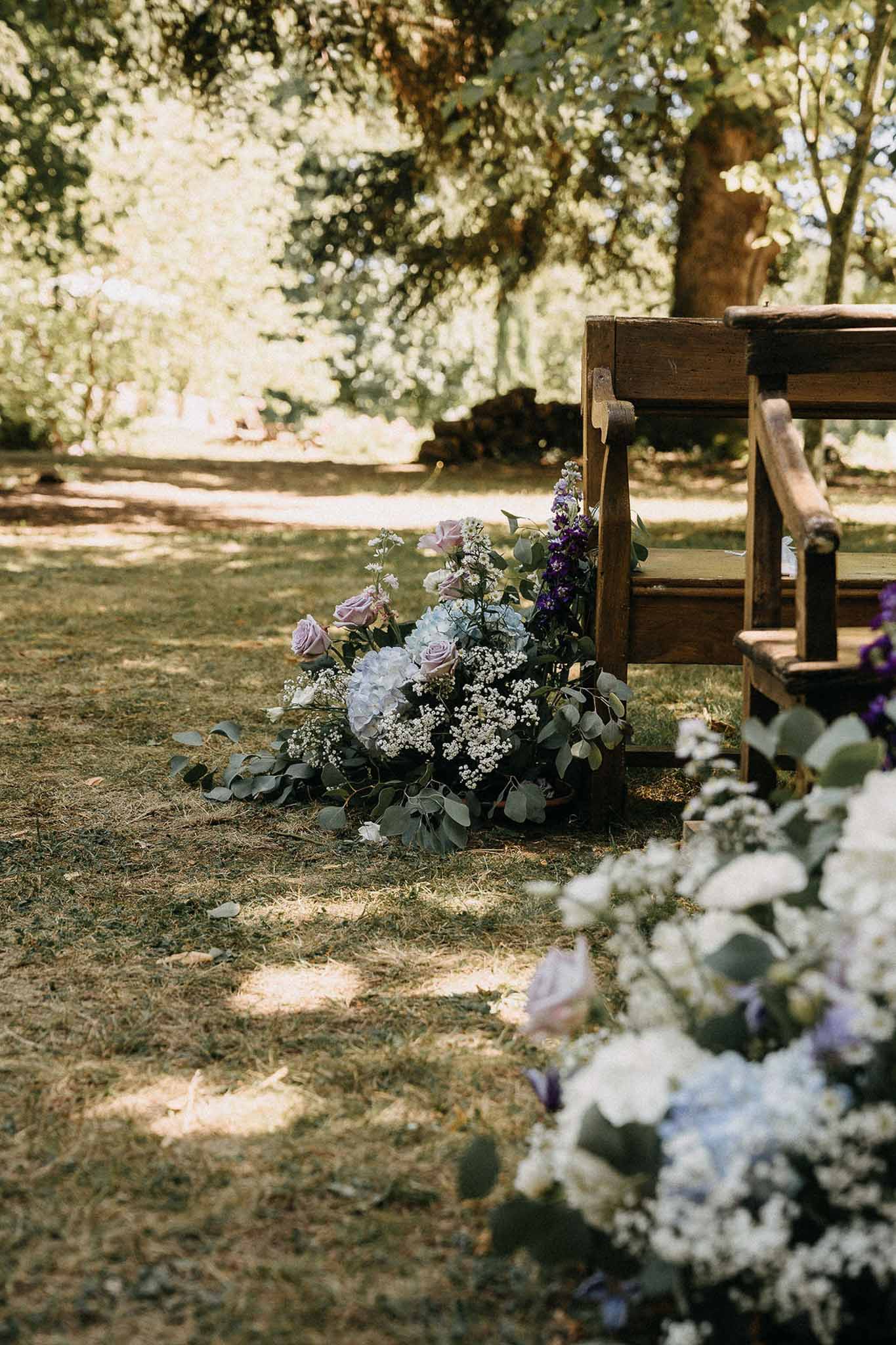Ceremony aisle arrangement of mauve roses blue hydrangeas purple delphiniums and eucalyptus