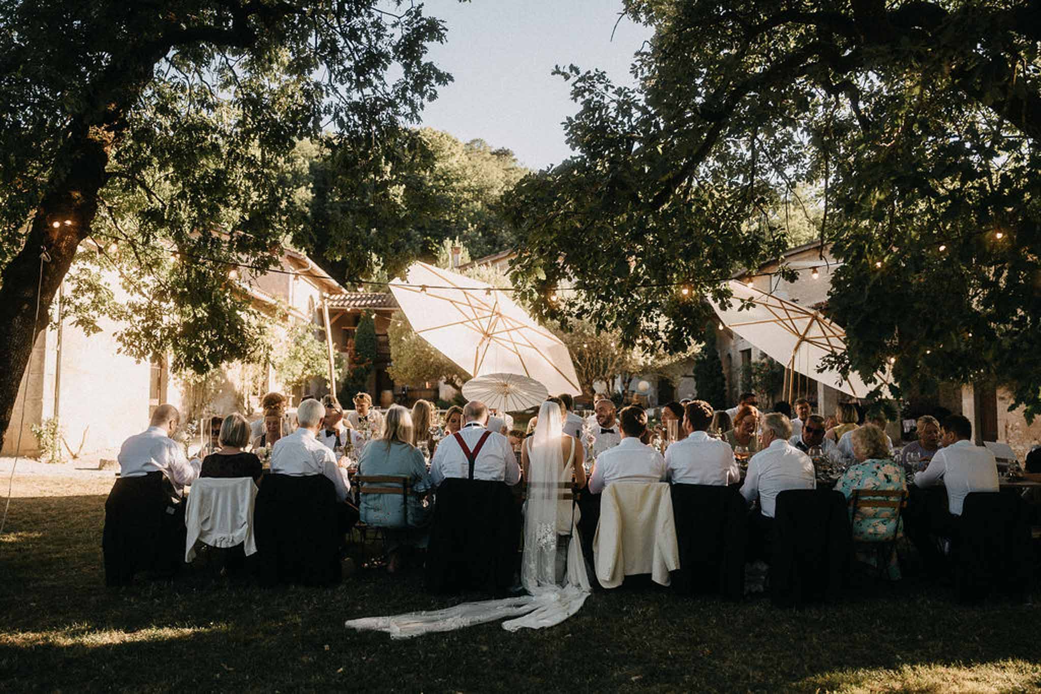 Outdoor reception with 35 guests under cream umbrellas and fairy lights at stone property
