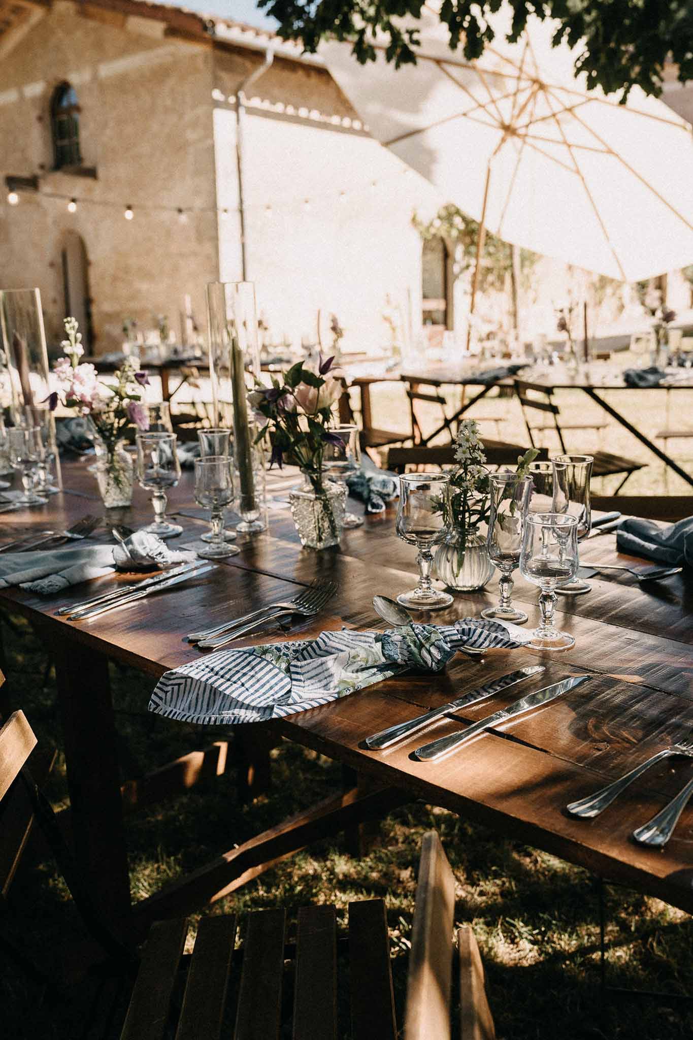 Rustic farm table with mismatched vintage goblets mauve clematis sage taper candles and botanical print napkins