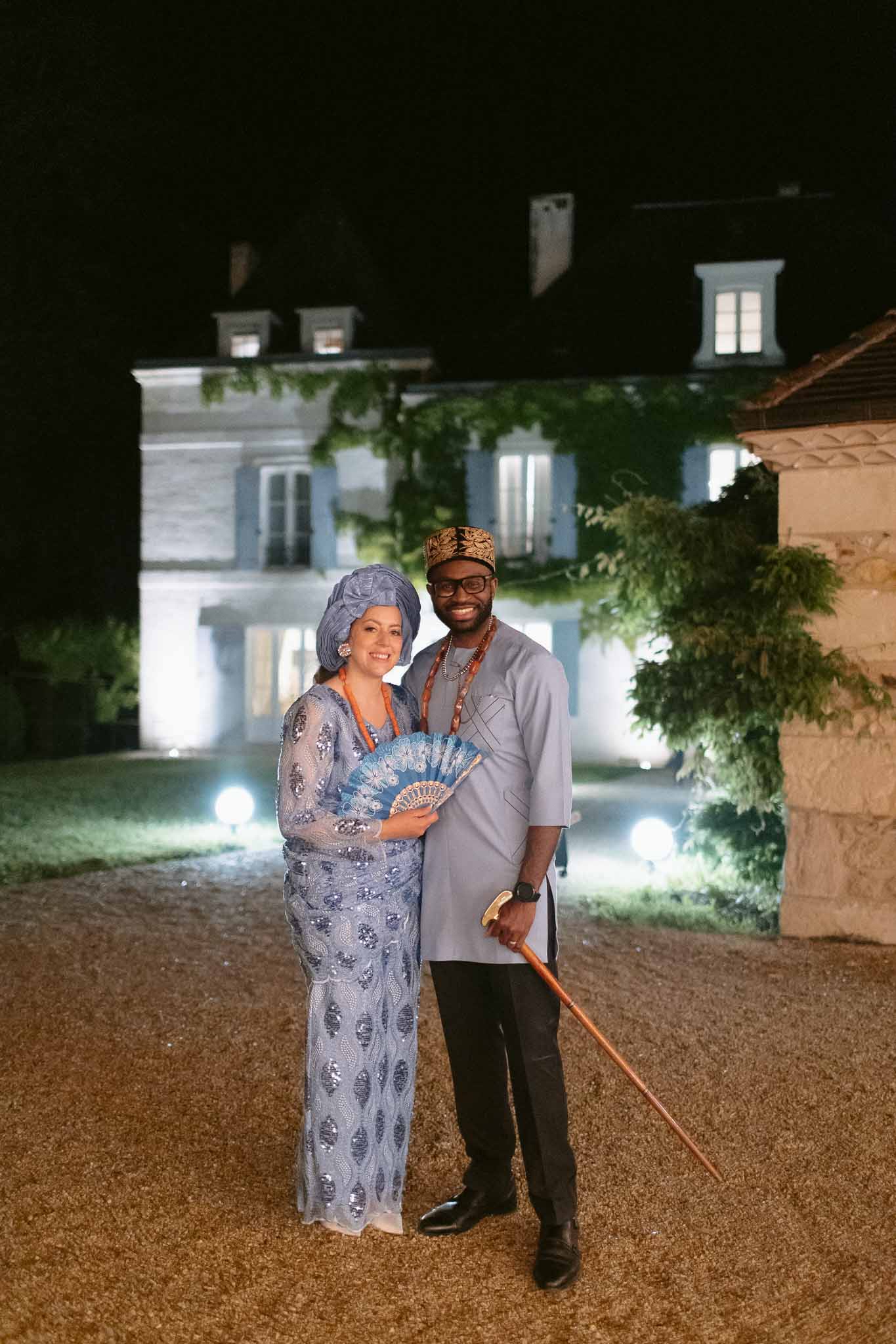 Couple in traditional Nigerian attire posing at night in front of illuminated French chateau