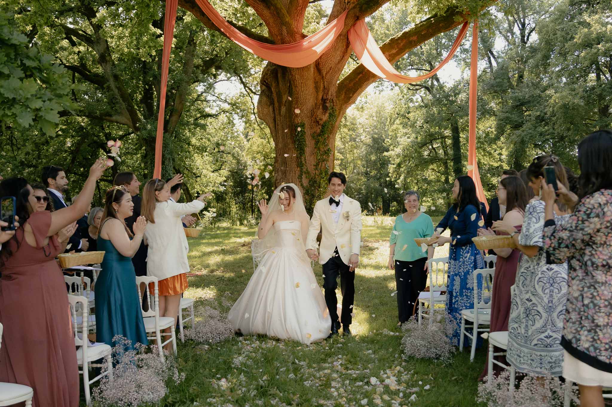 Couple recessional under yellow petal toss with baby's breath aisle and coral-draped oak tree behind