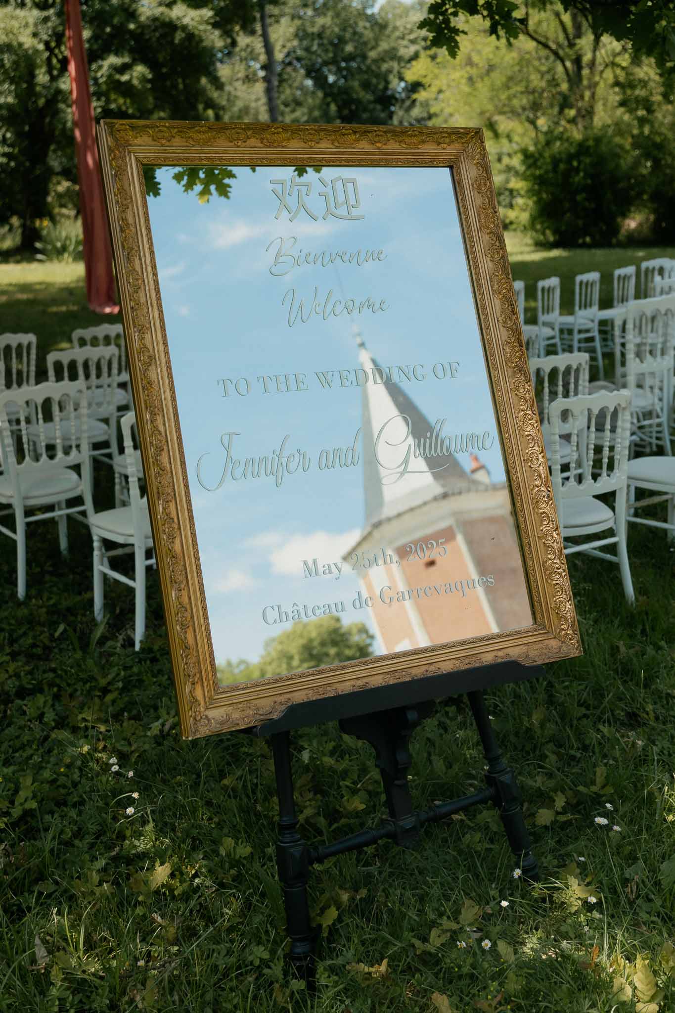 Gold-framed mirror welcome sign in Chinese, French, and English on easel with Napoleon chairs behind