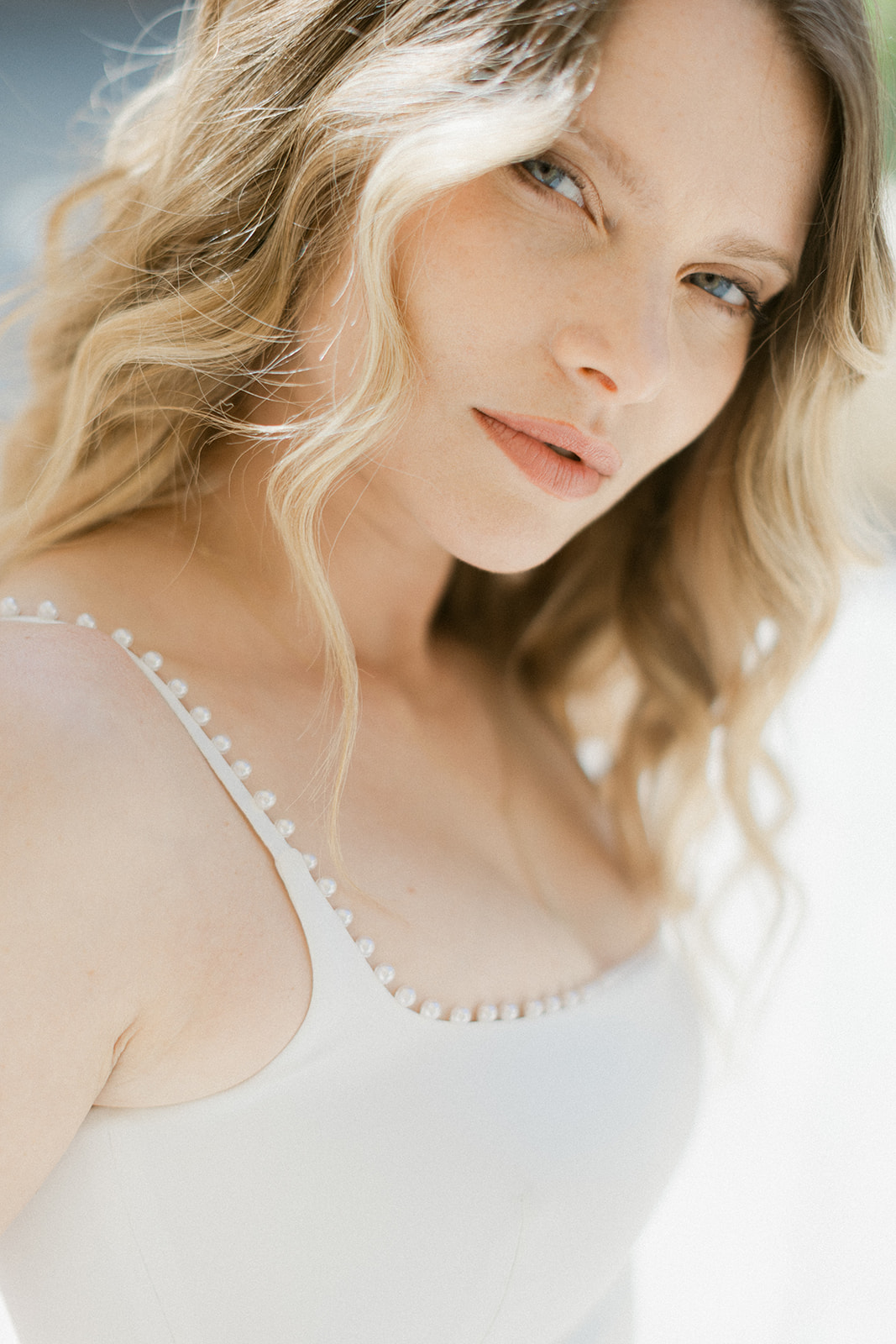 Close-up portrait of blonde bride with pearl-trimmed scoop neckline gown in natural light