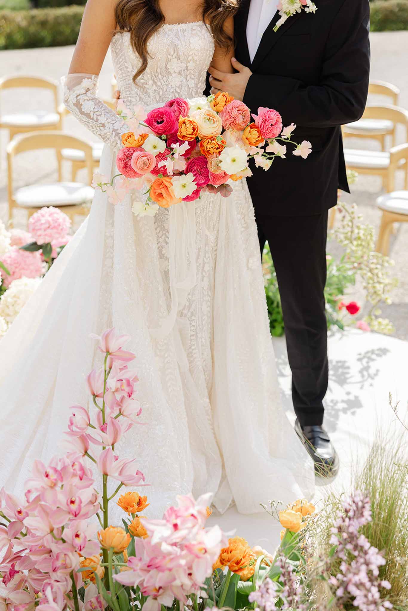 Bride holding pink and blush bouquet with groom during ceremony at Château Martinay