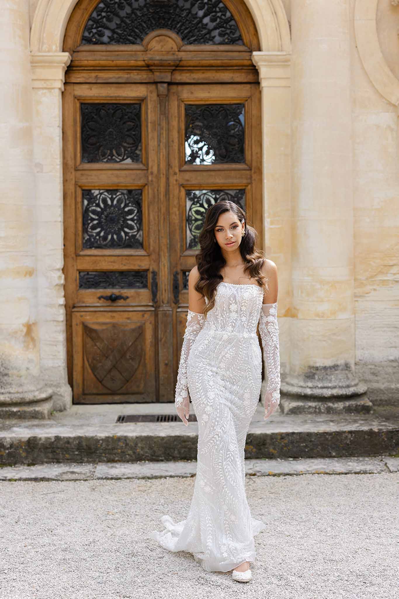Bride in lace mermaid gown and gloves walking in gardens of Château Martinay