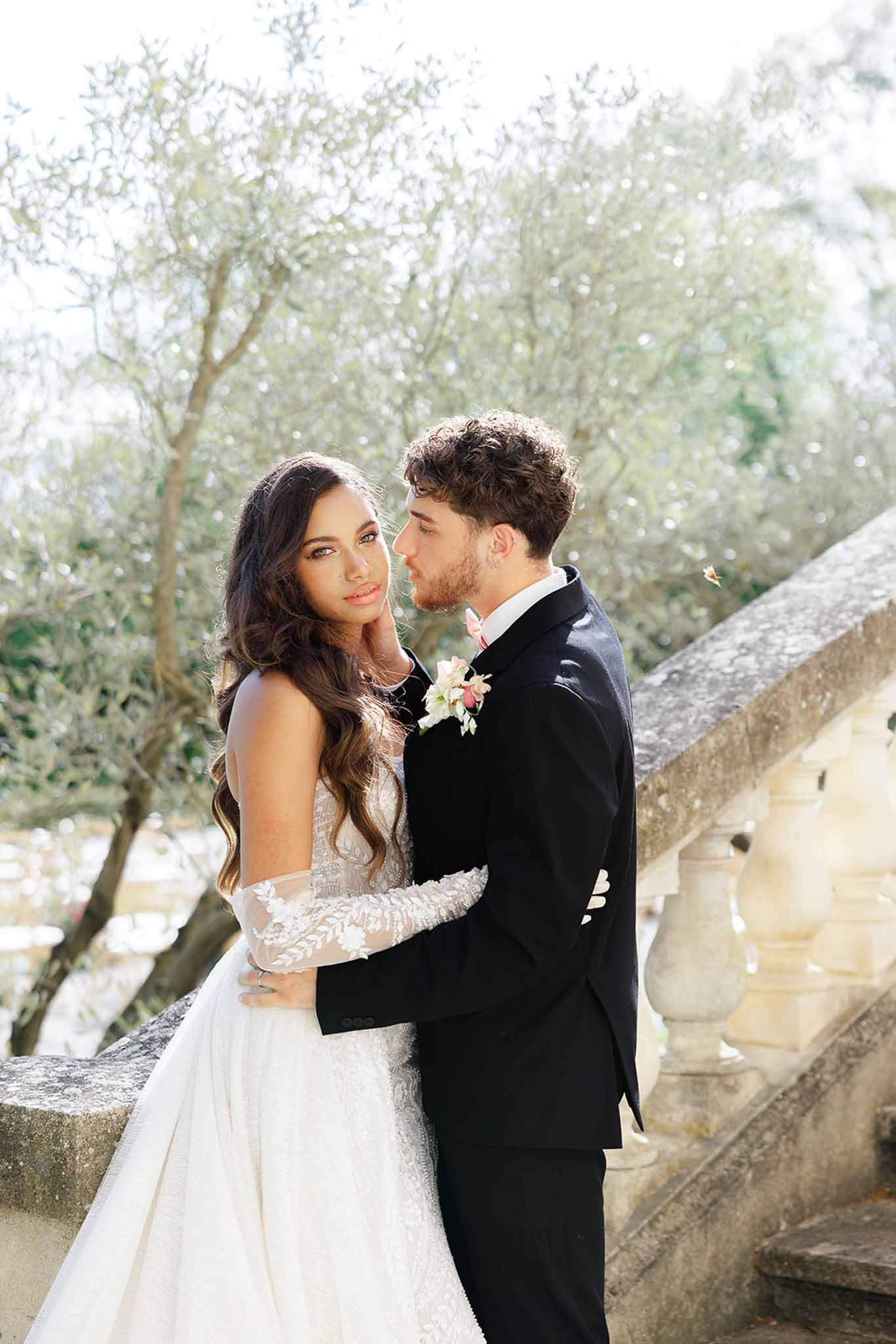 Bride and groom embracing on stone stairs outside Château Martinay