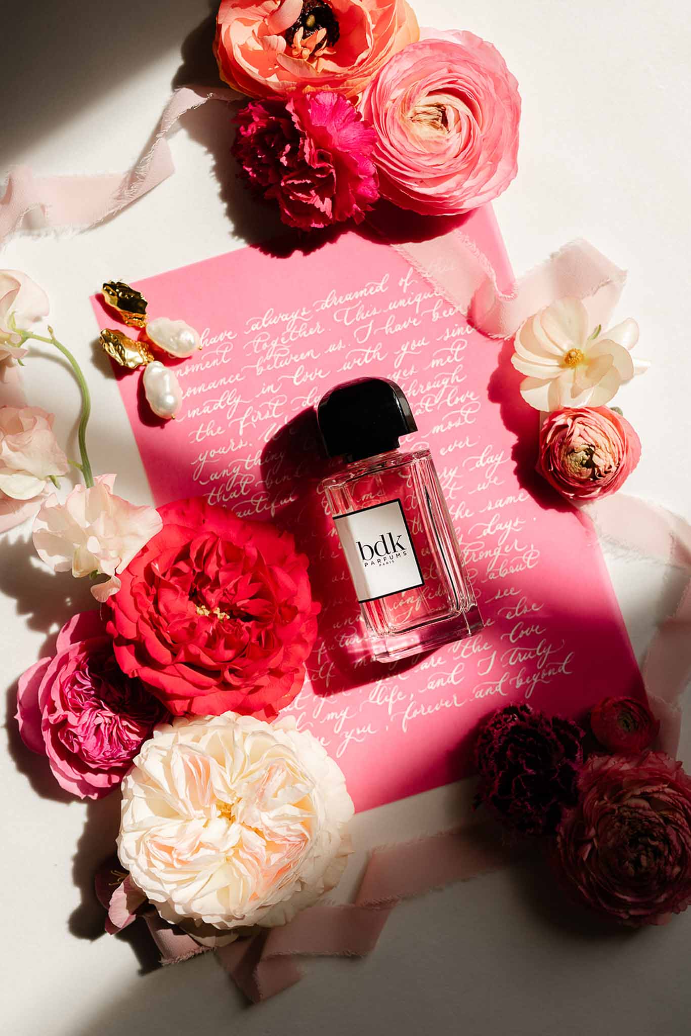 Flat lay of pink invitation suite with perfume bottle, Château Martinay styled shoot