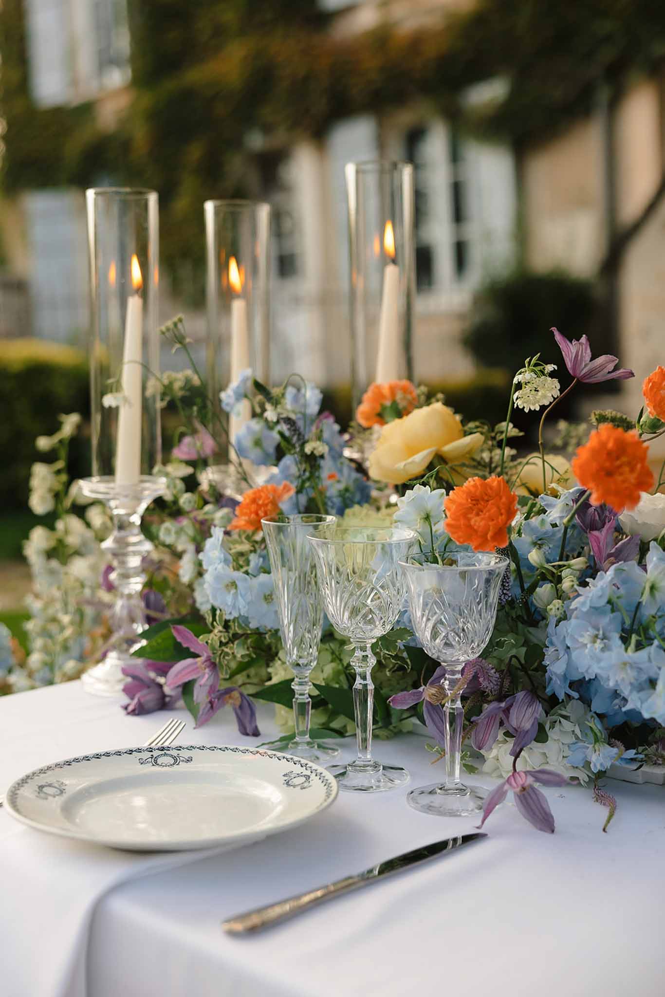 Place setting with medallion china, orange marigolds, blue hydrangeas, and purple clematis centrepiece