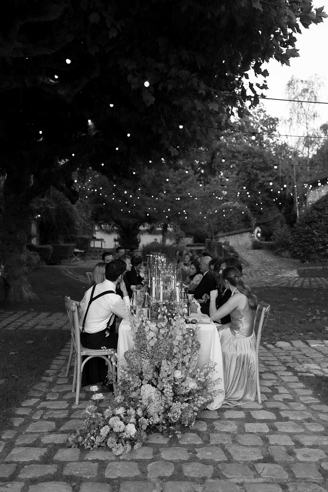 Black and white photo of wedding reception table setting in a garden with white roses