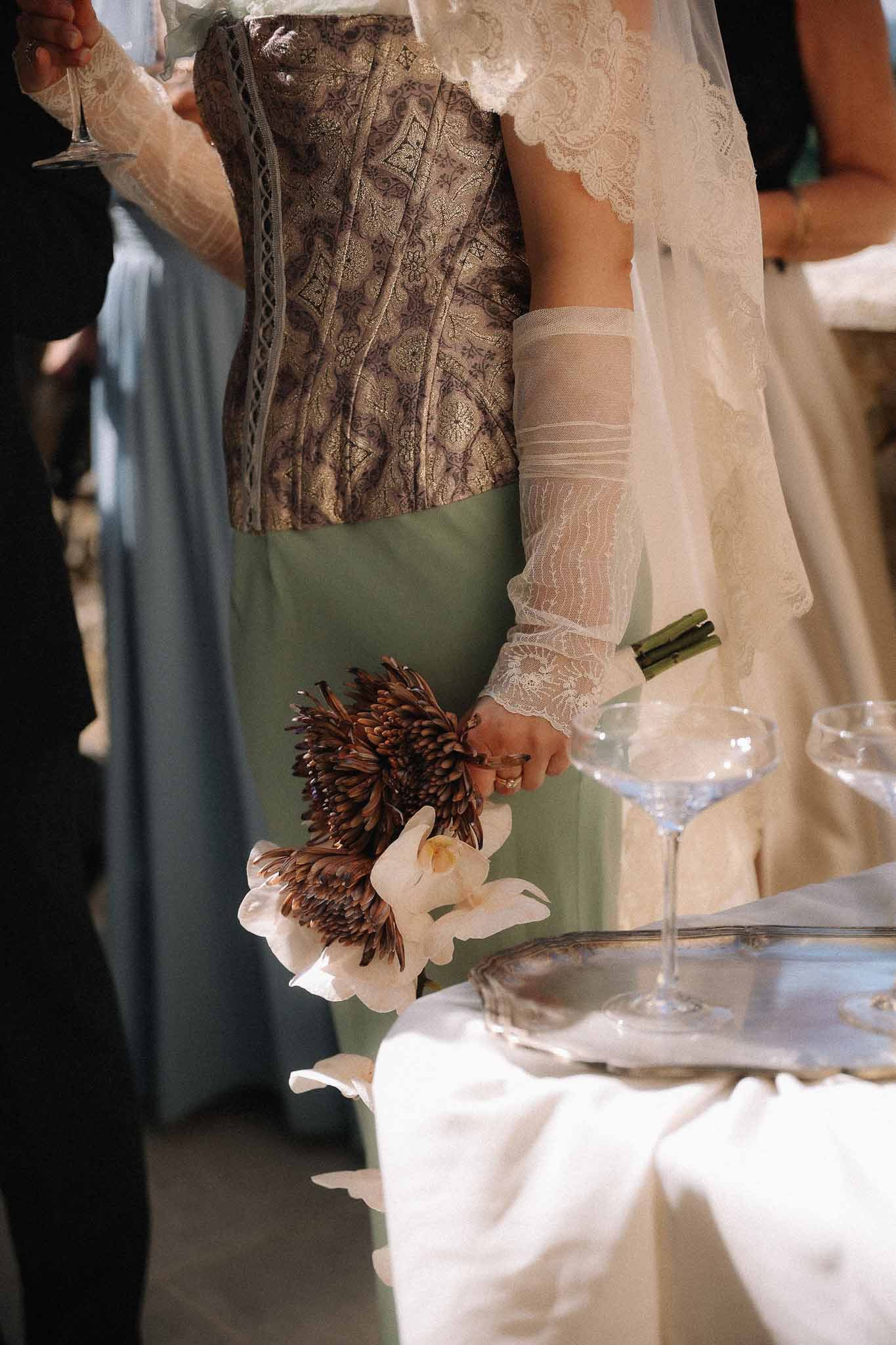 Bride holding white orchid bouquet wearing vintage gloves at Chateau St Victor Lacoste