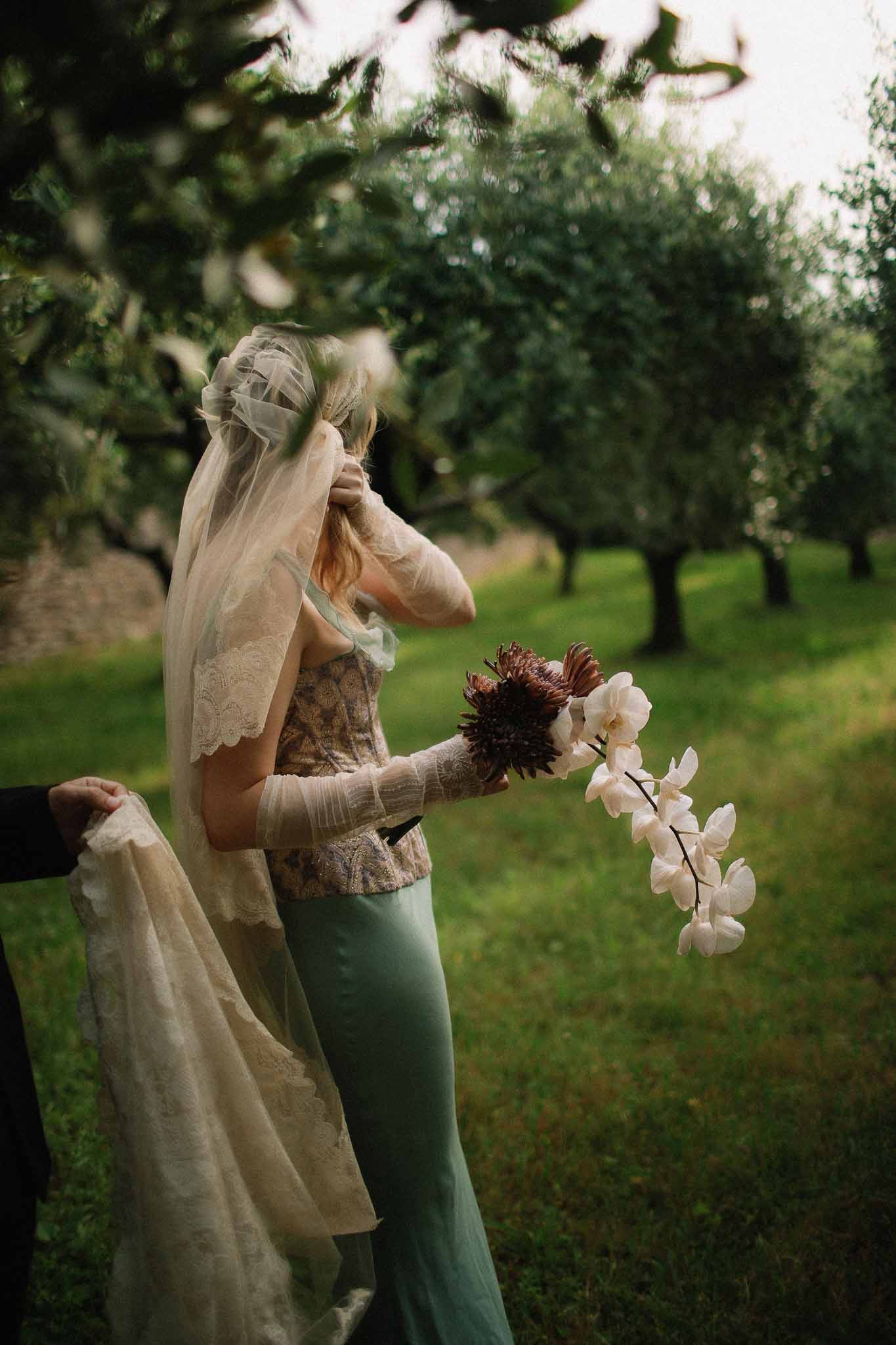 Bride holding unique white orchid bouquet while walking at Chateau St Victor Lacoste