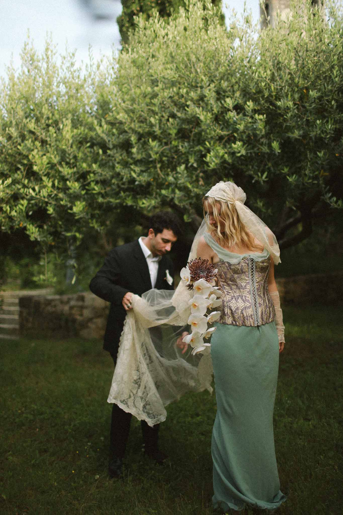 Groom helping fix bride's dress at Chateau St Victor Lacoste