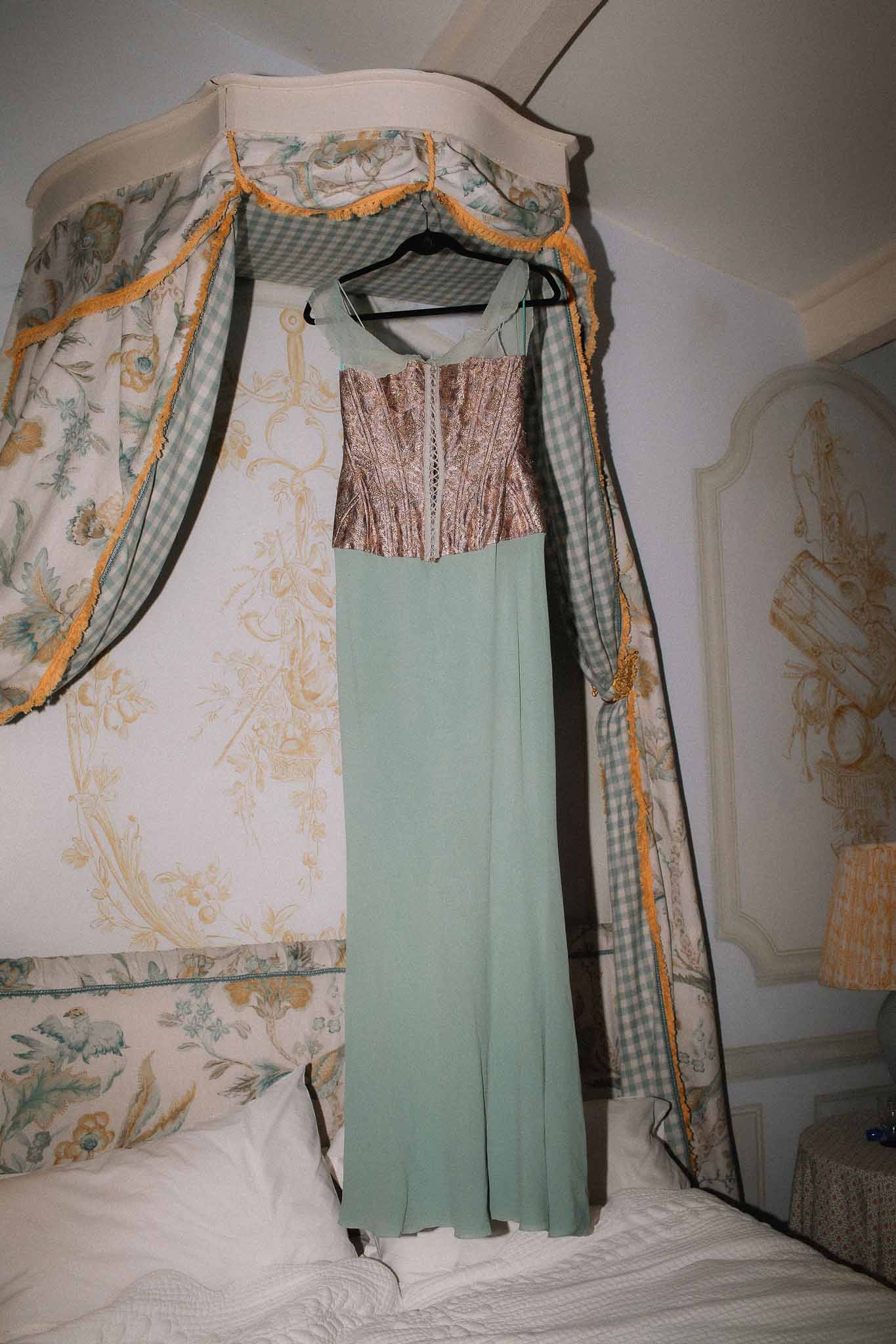Wedding dress hanging from bed in vintage bedroom at Chateau St Victor Lacoste
