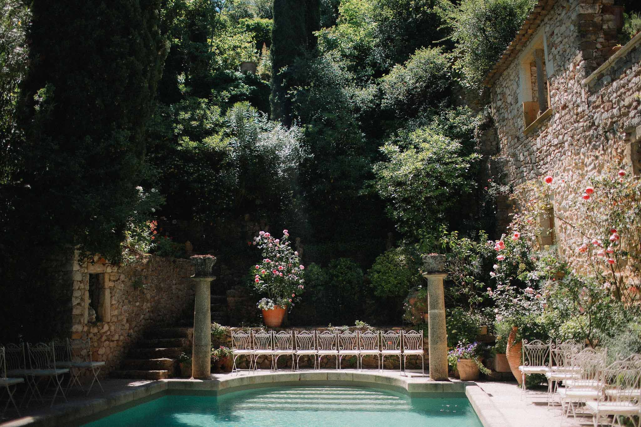 Wedding ceremony seating arranged poolside in the garden at Chateau St Victor Lacoste